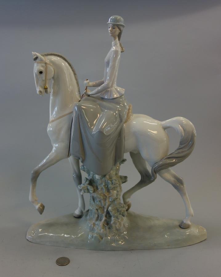 Lladro, Woman on Horseback "Amazona": A Lladro porcelain figural group, Woman on Horse or Amazona #4516, sculpted by Fulgencio Garcia. Depicts a lady riding side saddle on a prancing white steed. Blue Lladro mark underfoot. Handmade in Sp