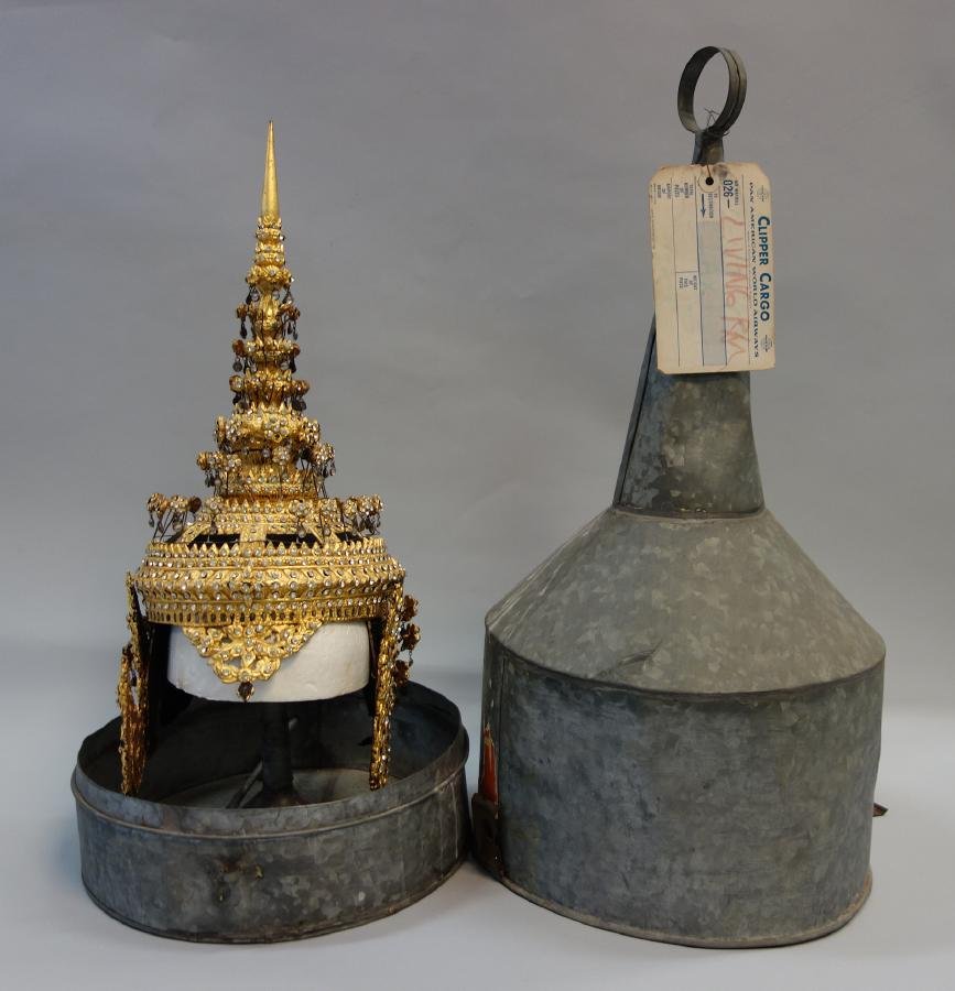 Balinese Tibetan Headdress & Hat Case: A Balinese or Tibetan parade headdress. Gold foil over structure with attached faux diamonds. Measures 18" high. Included is a tin metal storage hat stand and case measuring 26" high, 11" in diameter,