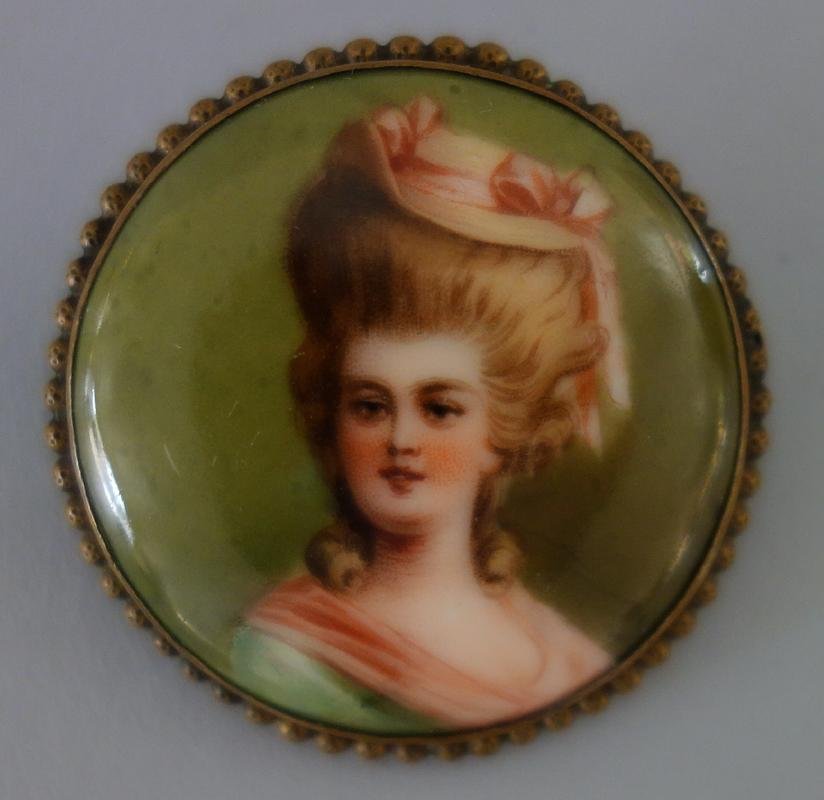 French Porcelain Plaque Brooch Pin: A hand-painted porcelain round plaque, mounted as a brooch pin in a gilt metal beaded surround. Depicts a young woman in a hat, possibly Marie Antoinette. The porcelain impressed with the number 7. Me