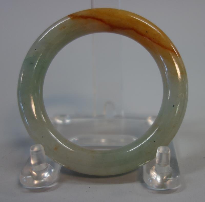 Chinese Translucent Jade Bangle Bracelet: A Chinese jadeite jade bangle bracelet. Green / white and russet jade. Measures 2-7/8" in diameter, 7/16" thick.