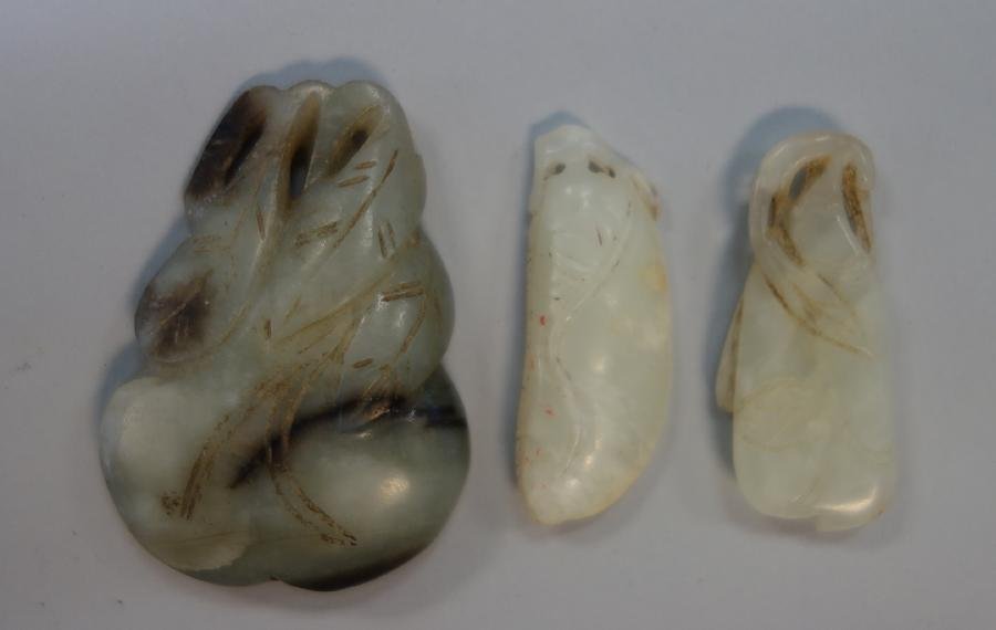 3 Chinese Jade Carved Toggles: A group of three Chinese carved jade toggle / pendants. The largest measuring 2" high x 1.5" wide depicts a leaf gourd or fruit. The two smaller white jade carvings measure 1.5" x 5/8".