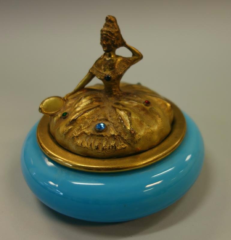 French Opaline Glass & Bronze Figural Box: A French / Continental blue opaline glass powder box / jar. Bronze figural cover depicting a lady in a ball gown holding a mirror, the dress adorned with glass jewels. Measures 4.25" high, 5.5" in dia
