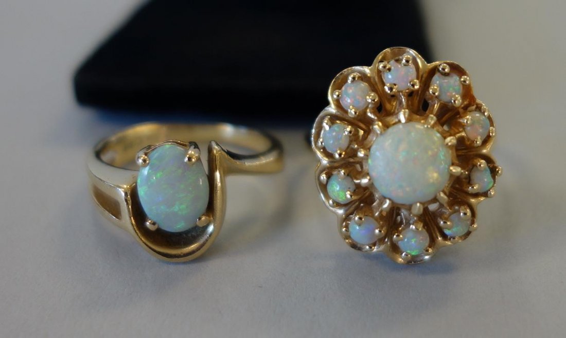 2 Opal & 14K Gold Rings, Flower Form & Modernist: Two opal cocktail rings. Each set in 14K gold. A flower formed ring set with a center cabochon surrounded by ten smaller stones. Ring size 6.5. Together with a solitaire oval opal set in a Modernist s