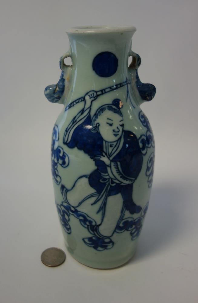 19thc Chinese Celadon Vase: A Chinese celadon ground vase with underglaze blue enamel decoration depicting a young male holding a staff among stylized clouds. Foo lion / dog formed handles. Measures 8.5" high, 4" wide.