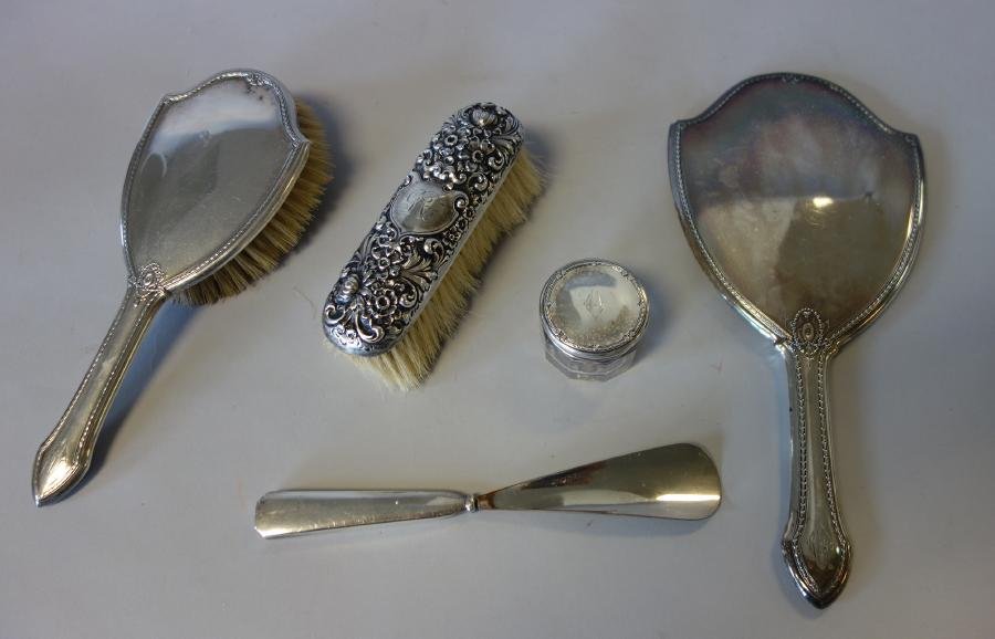 Sterling Silver Brushes, Mirror, Shoehorn & Jar: A sterling silver clothes brush with an embossed overall floral motif. Together with a sterling hair brush, a sterling hand mirror, sterling lidded glass jar, and a sterling handled shoehorn. Various