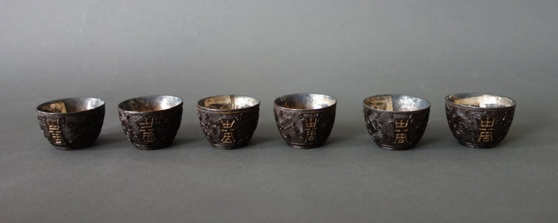 6 Chinese Carved Horn Wine Cups: A set of six Chinese horn wine cups with removable silver interiors. Each finely carved in raised relief with Chinese symbols and precious objects against an overall geometric motif. Measuring 1.75" d