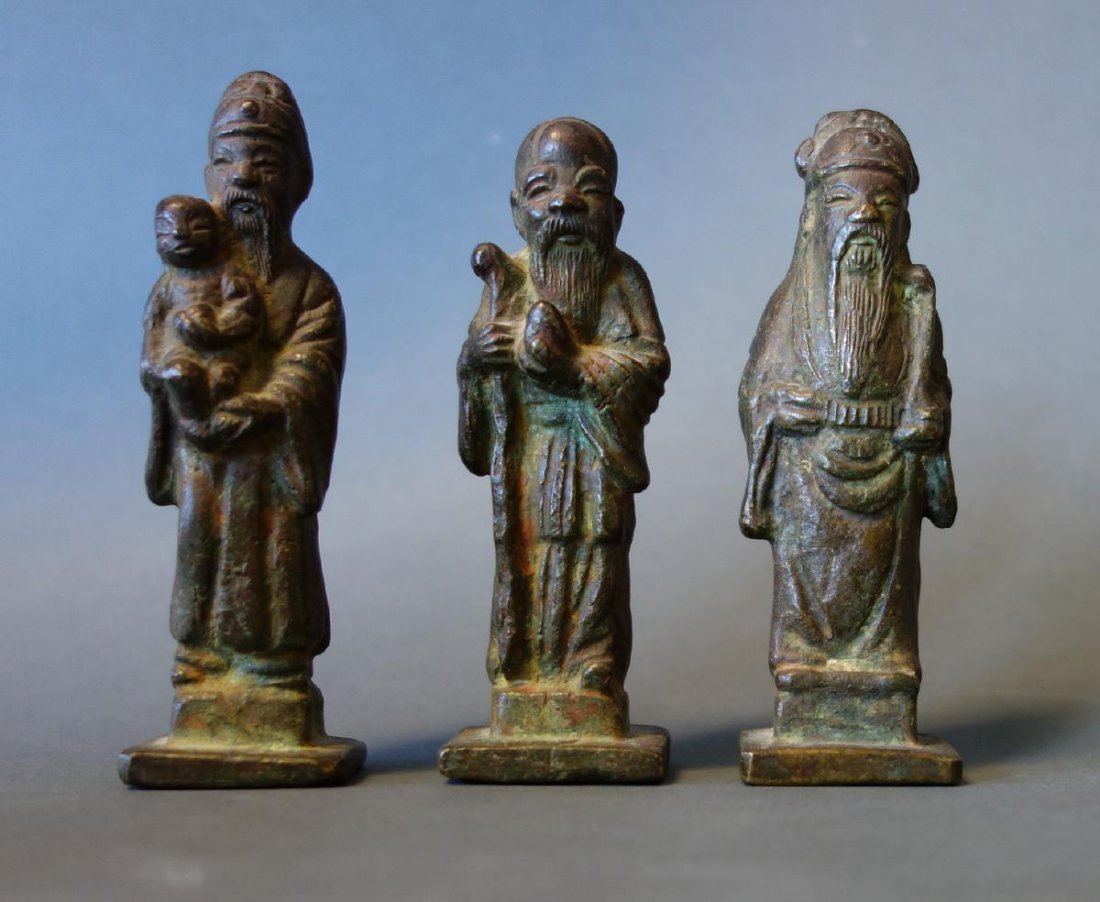 Chinese Bronze Set of the Three Star Gods: A Chinese bronze set of the Three Star Gods. The figures represent, Fu, the symbol of good fortune, depicted in scholar's dress, holding a child, Shou, the symbol of longevity recognized by his high d