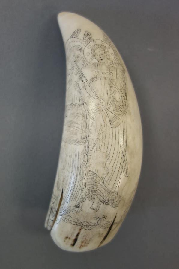 Antique Scrimshaw Whale's Tooth, 19thc New England: An Antique scrimshaw whale's tooth. 19th century, New England. Finely decorated with the depictions of three angels, two with trumpets (Angel Gabriel) and one with a shield. Measures 5.5" long, 2" wid