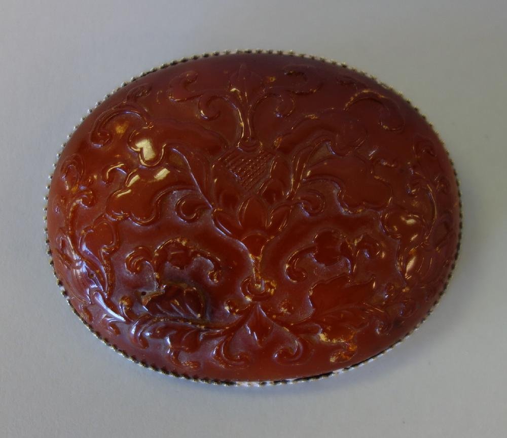 Large & Fine Carved Carnelian Brooch: A carnelian oval brooch pin. Finely carved depicting an urn filled with abundant flowers and foliage. Set in a sterling filigree mounting. Measures 2.75" wide, 2.25" high, .5" deep.