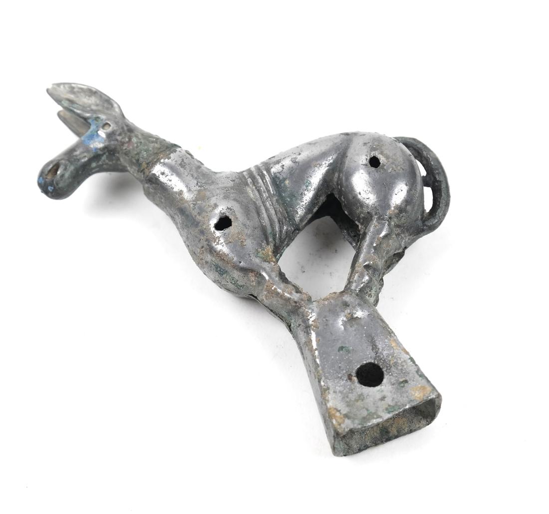 AN ASIAN ORDOS SILVER UNGULATE-FORM FINIAL: The figure modeled as on a trapezoidal socket, pierced through two areas of the body and through the socket; head possibly replaced, areas of blue-green encrustation 5 7/8 in. high, cloth box