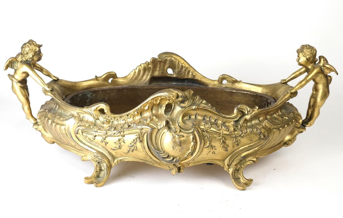 Rococo-Style Gilt Metal Petite Planter: Oval-form, having cherub-form handles. [19 1/2" W x 8 3/4" D x 7 1/2" H]. Wear and rust.