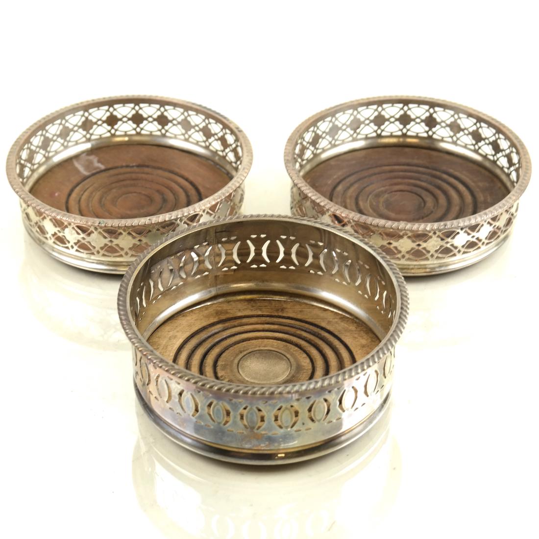 3 Similar Silver-Plated Wine Coasters: Early 20th century, comprising: a pair and a similar example, all with pierced gallery and turned wood base; [H: 1 3/4in & 2 1/4in; Dia: 5 1/4in]; All with some wear overall.