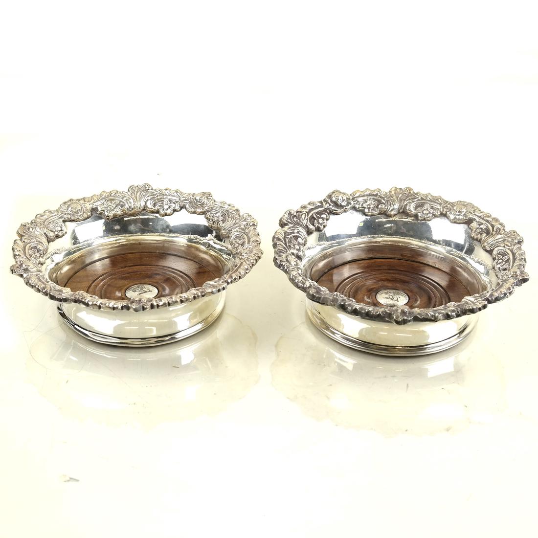 Pair Silver-Plated Decanter Coasters: 20th century; each with applied cast foliate border; the center engraved with lion's crest; [H: 2 1/4in; Dia: 7 1/8in]; Some wear overall.