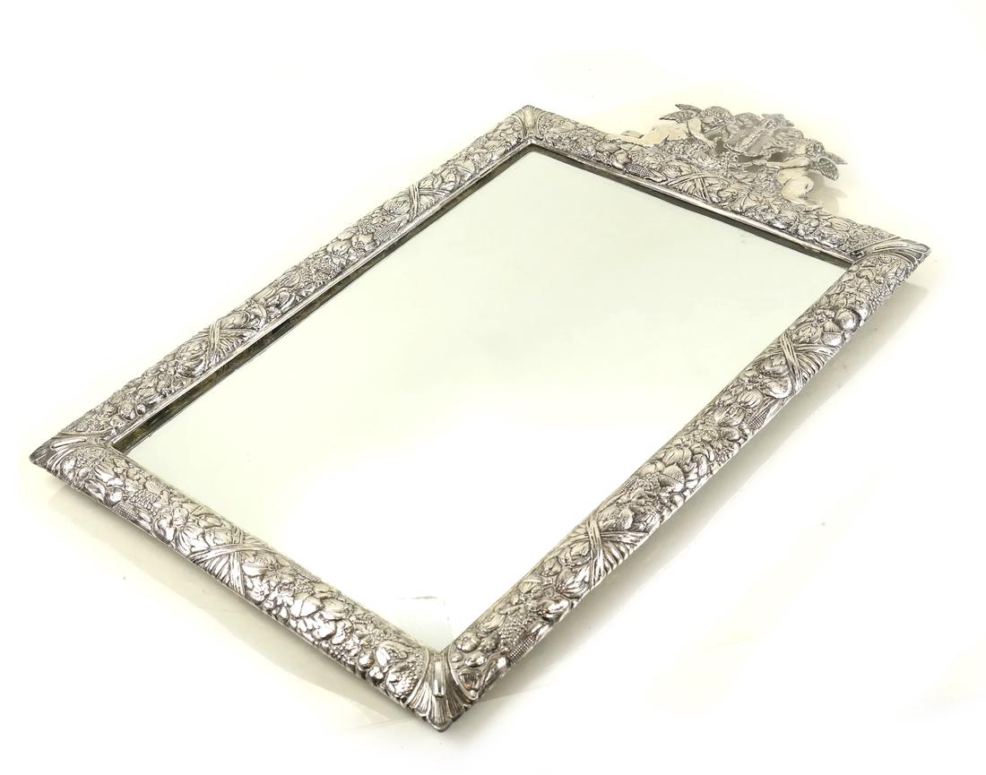 Continental .800 Silver Framed Mirror: Continental .800 standard chased silver framed mirror, Probably Hanau, circa 1900, the silver border chased all over with numerous fruits and vegetables, with cherub armorial crest surmount; [H: 22in;