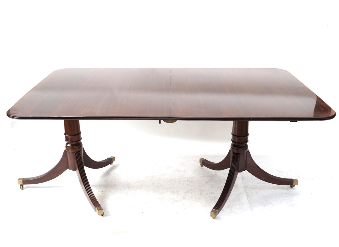 Sheraton-Style Double Pedestal Table: English mahogany banded border double pedestal dining table, accompanied by three leaves. By Rackstraw, England. [30 1/2" H x 71" W x 44" D; Leaves:18" each]. 300