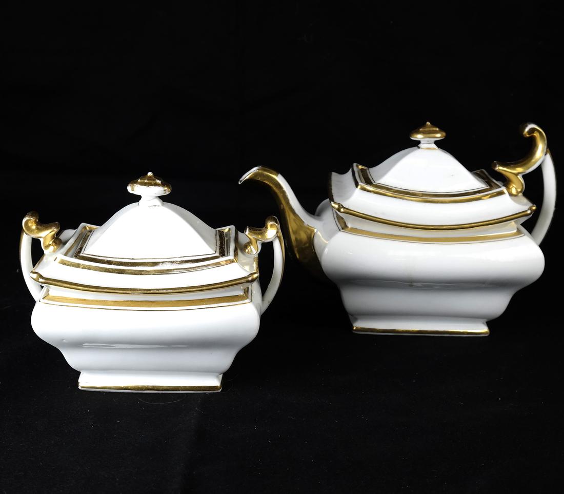 Paris Porcelain Teapot & Sugar Bowl: Late 19th century, each of rectangular section, with shaped sides and scroll handles, and with wide gilt borders; [H: 7" & 6"; L. over handles: 10 1/4" and 7 1/4"]. Each with repaired finials, with so