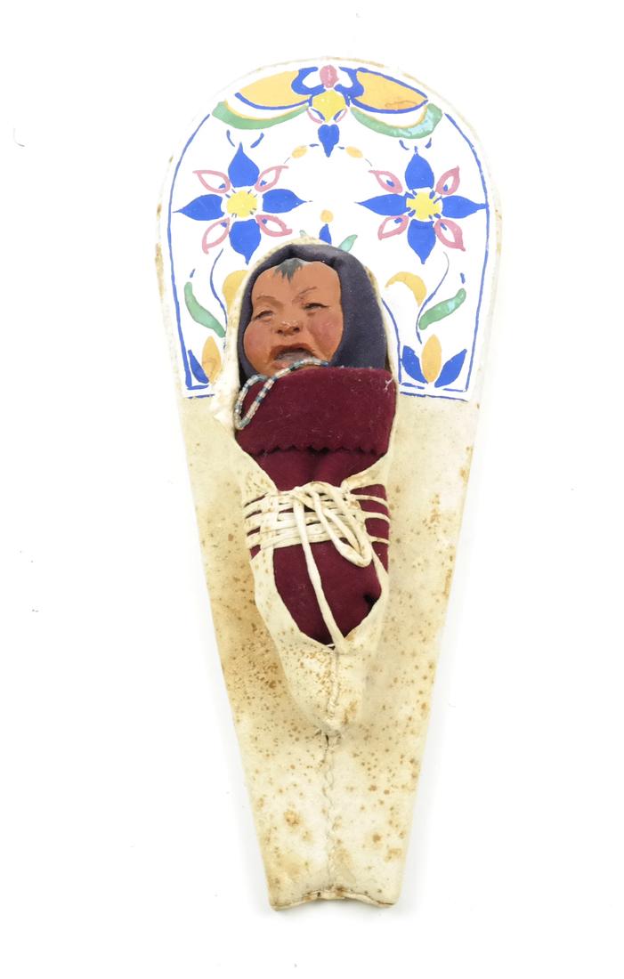 Papoose on Panel: Native American Indian doll wrapped in hide, mounted on panel. Signed Joe De Hong and dated.