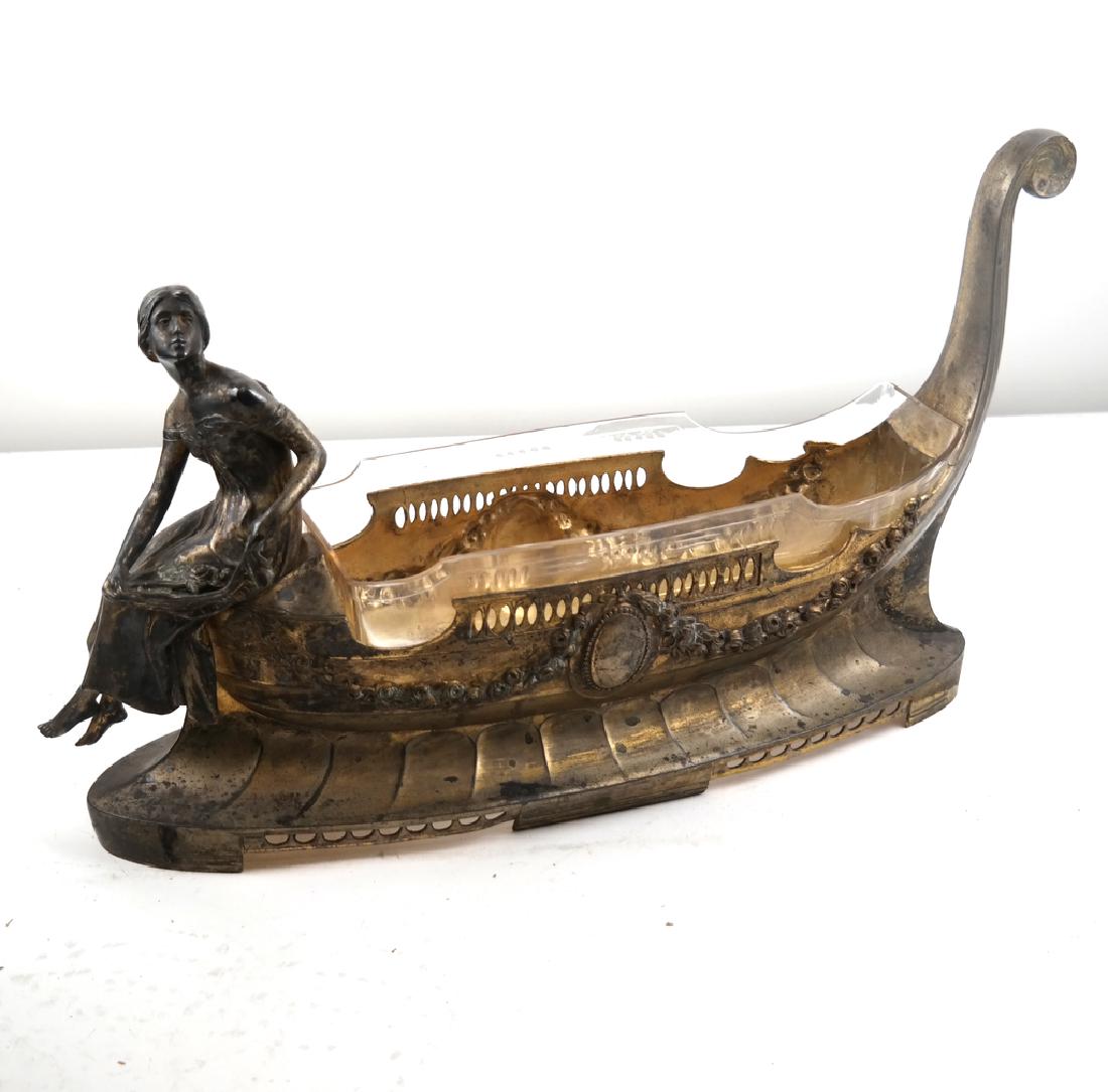Figural Gondola Brass & Crystal Centerpiece: A centerpiece having a woman seated on a gondola with a glass insert. Dimensions: 20" W x 5.5" D x 12"H; 