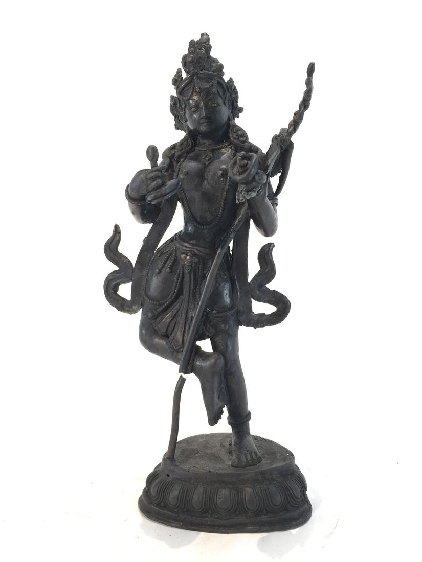 Buddhist Hindu Tibetan Deity: Old Hindu or Buddhist figure, depicting a deity standing atop a lotus base, the hands holding various implements, supporting a skull staff between his left arms. From a large estate collection of Asia