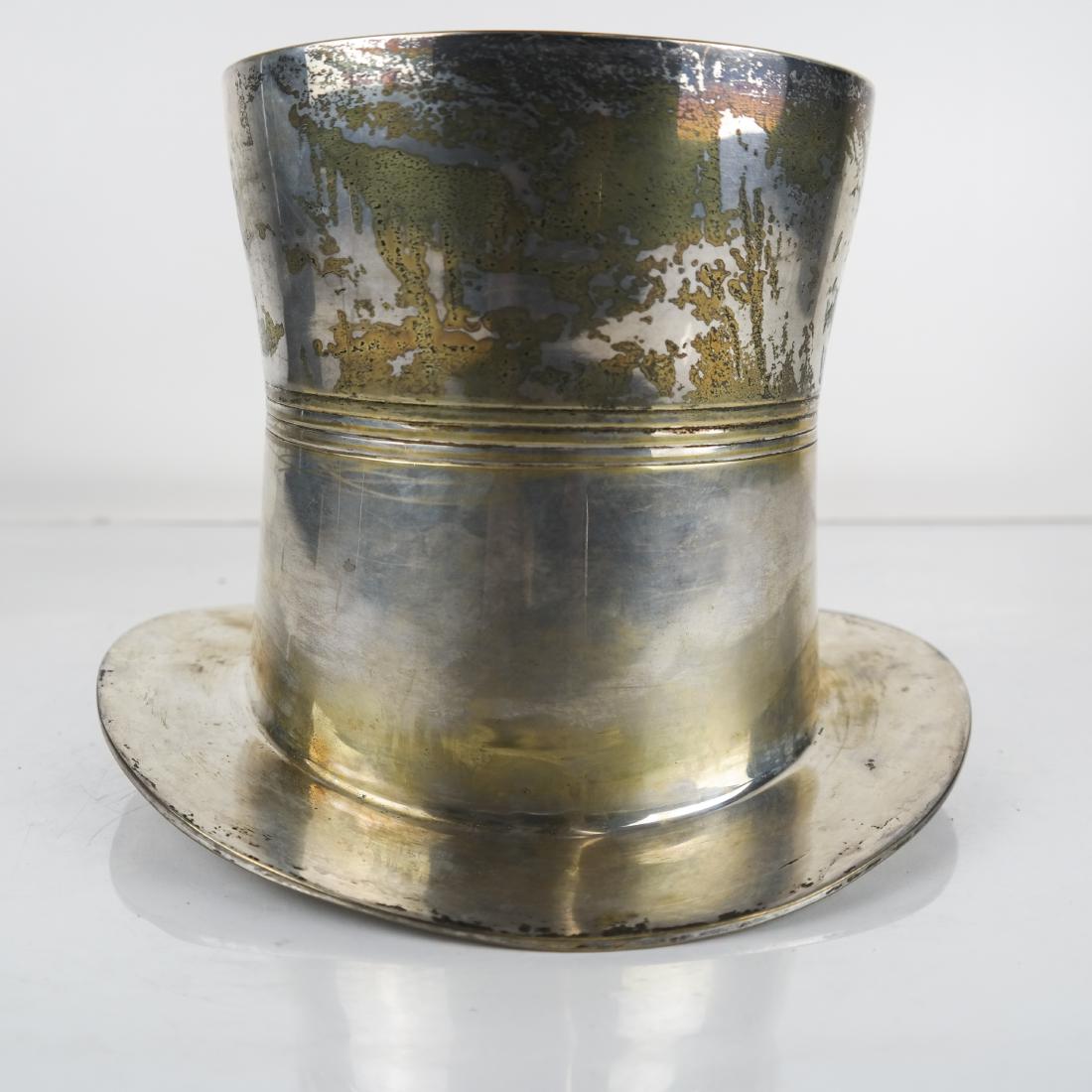 Silver Plate Top Hat Wine Cooler: Silver-plated top hat-form wine cooler/champagne holder, with reeded band around middle, bearing paper label "E.P.N.S. / India / Ware". 6 1/2 x 6 1/4 (dia) (base) inches; Outer edge of top rim: 9 1/4 