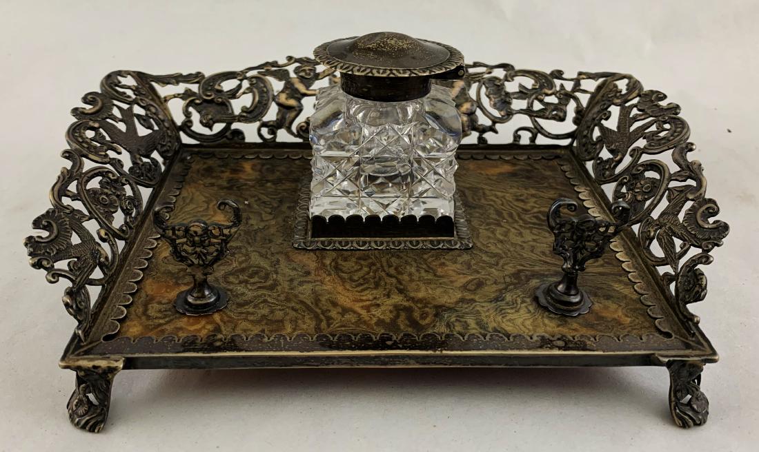 Sterling Silver & Shell Inkwell: English sterling silver and shell inkwell with winged putti holding crest [1.3/4 x 8 x 6 inches]. In good condition, small dent in top, pen holding nuts missing.