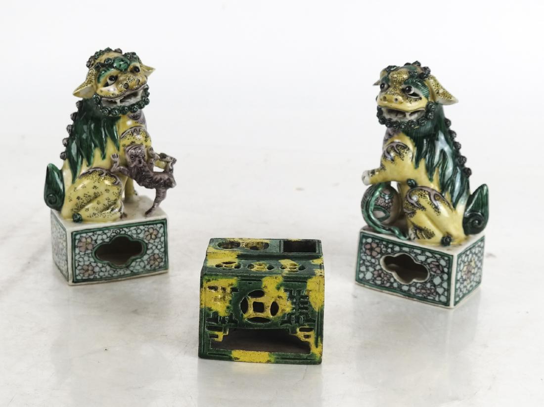 Pair of Chinese Foo Dogs and Another: A pair of Chinese opposing foo dogs and a small stand. [Largest: 5 x 2 1/2 x 1 3/4 inches]. Ears with chips.