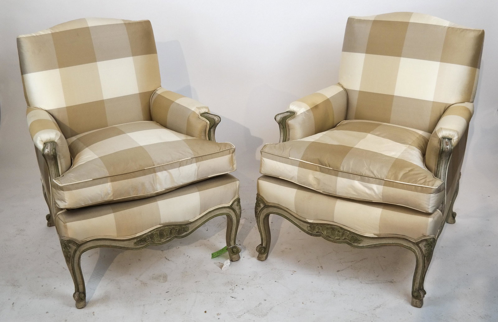 Pair of French Louis XVI-Style Bergeres: Pair of custom-crafted Louis XVI-style pickled wood bergeres, covered in a pale yellow and gold satin, on cabriole legs. In good condition.