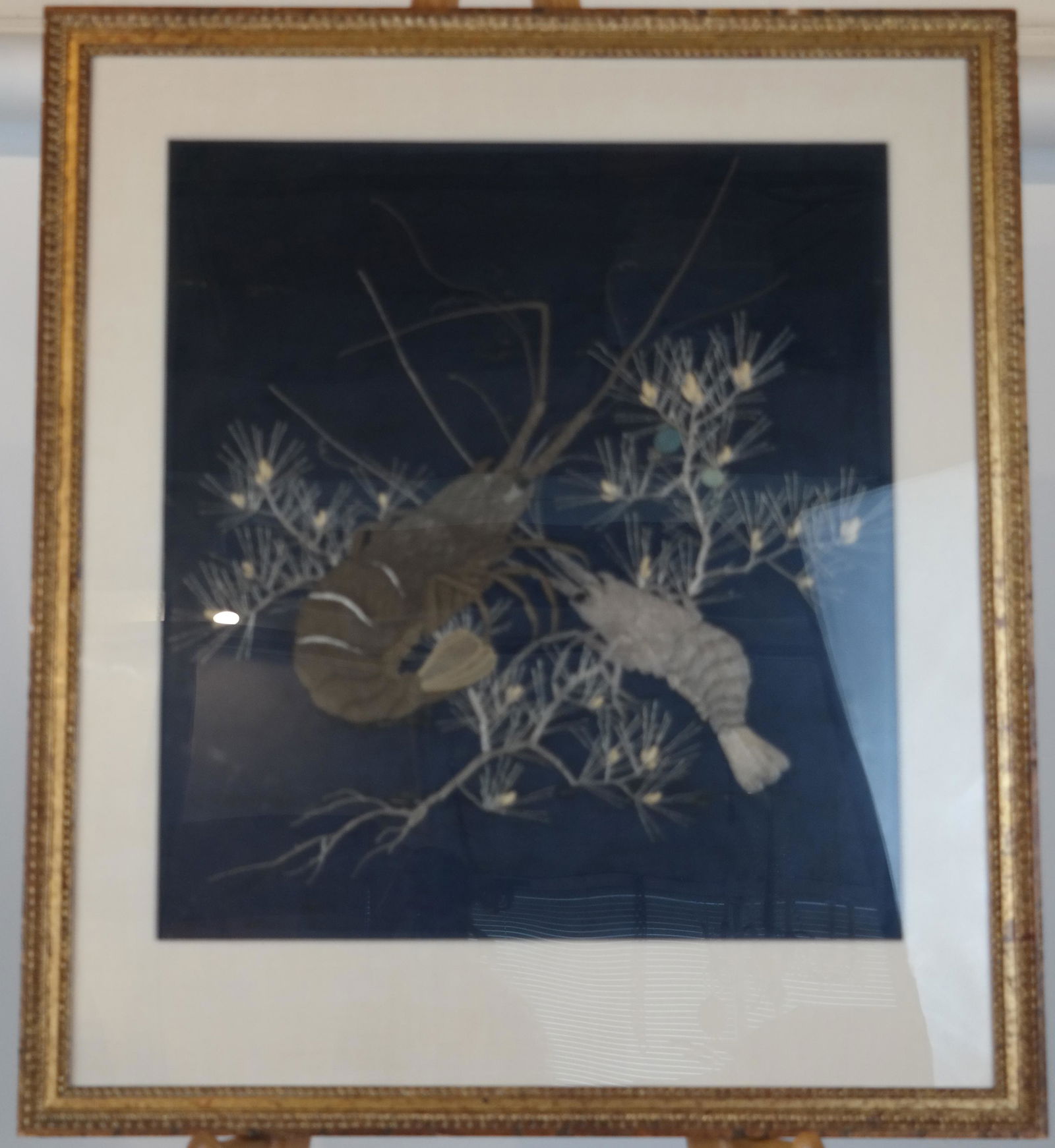 Japanese Crayfish Silk Embroidered Textile: Japanese gold couched thread embroidered picture on a black silk ground, circa 1900, of a crayfish and a pine, in a gilt frame. [25 x 25 inches]. In good condition.