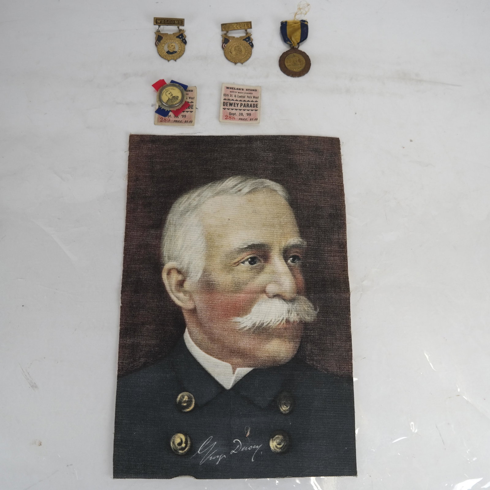 Admiral George Dewey Lot: Lot includes: 4 Welcome NY stickpins/pinbacks, 2 Dewey parade tickets, dated Sept. 30, '99 and Dewey printed textile in color [13 x 9 inches]. Color remains bright and vibrant on textile; stickpins/pi