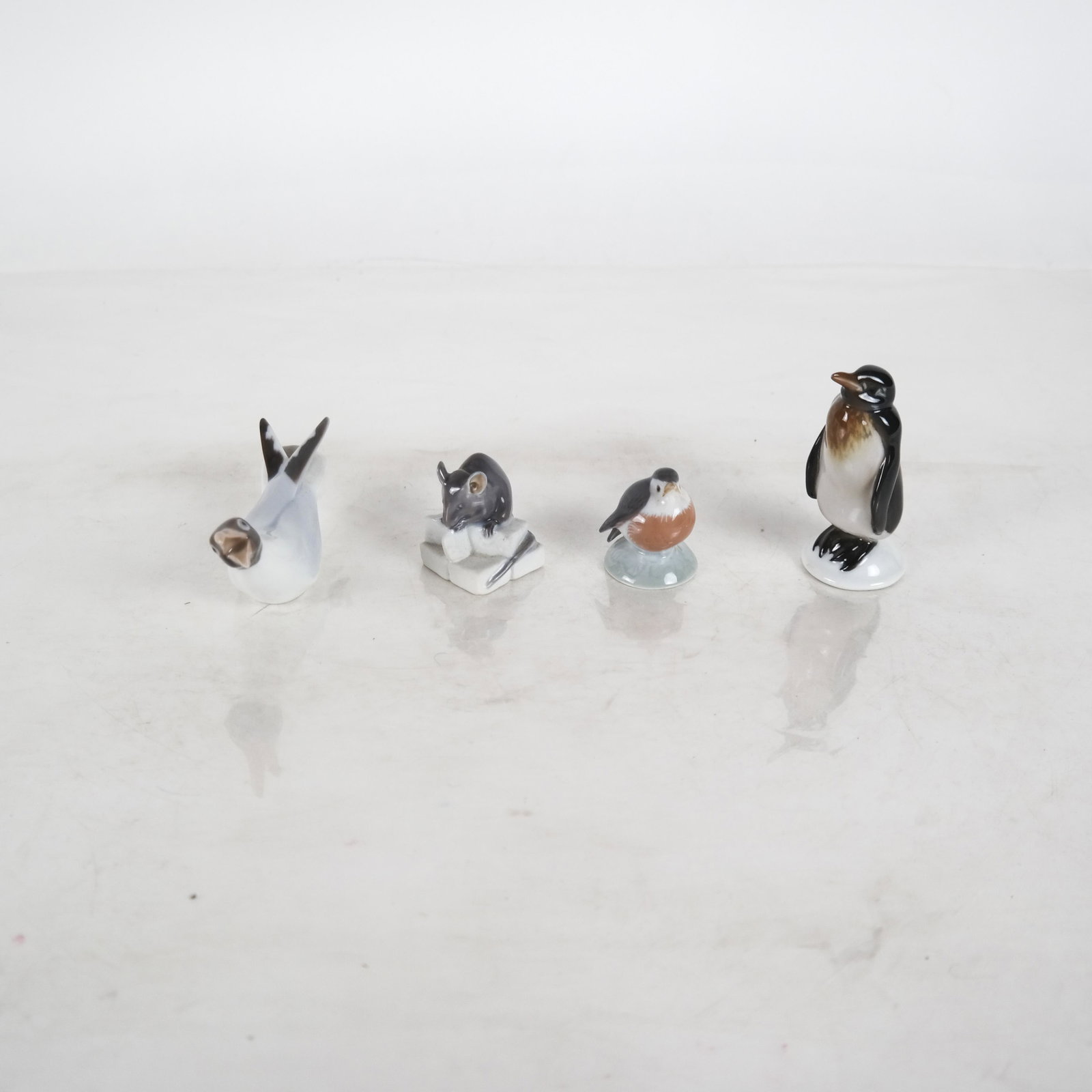 Four German and Danish Porcelain Animals: Lot comprises a Royal Copenhagen mouse and bird, a Bing and Grondahl Danish penguin, and a Rosenthal penguin. [3 inches high (largest) x 4 inches long (largest)].