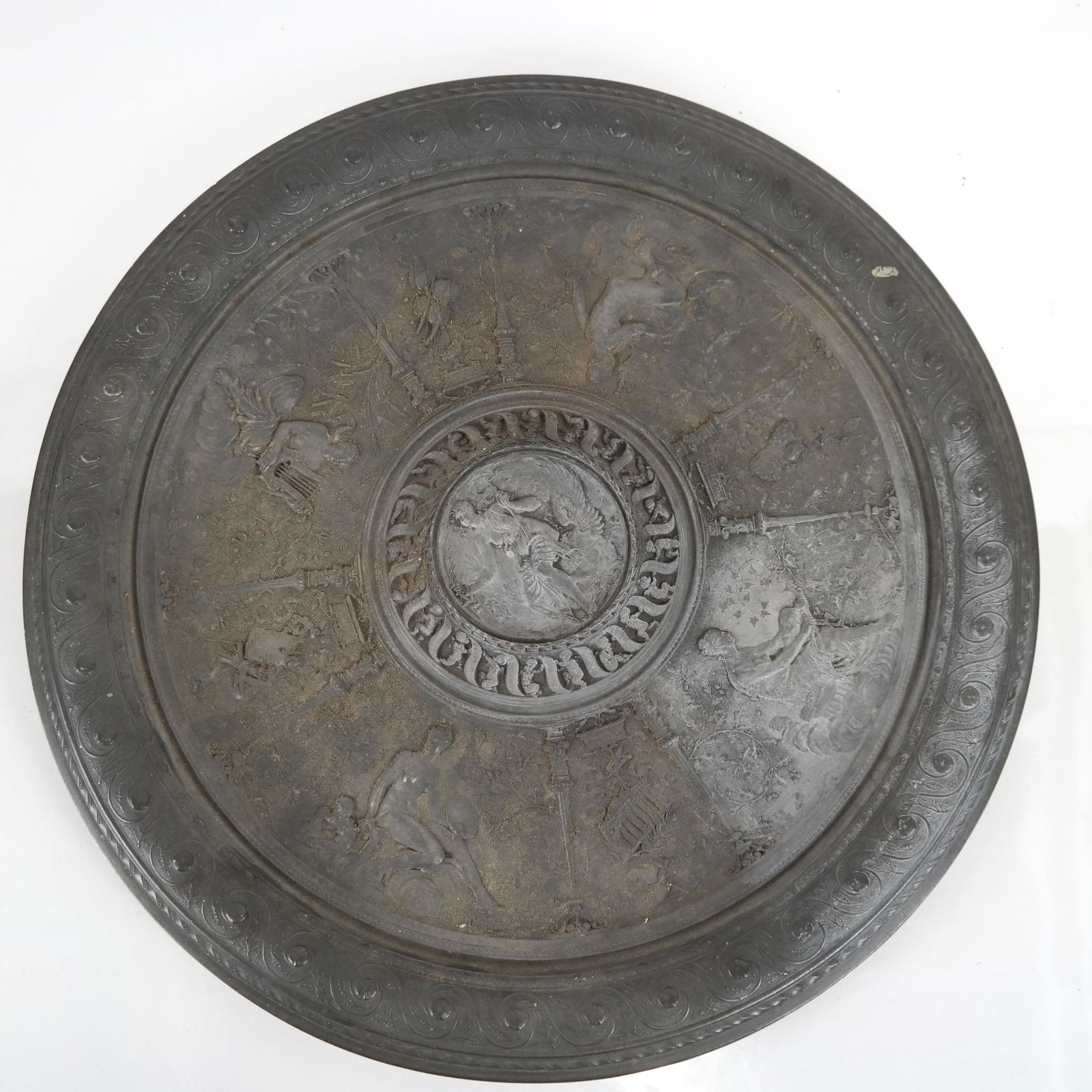 Pewter Figural Relief Charger: Pewter charger with classical figural reliefs representing The Arts. [16 3/4 (dia) inches]. Wear; tarnish.