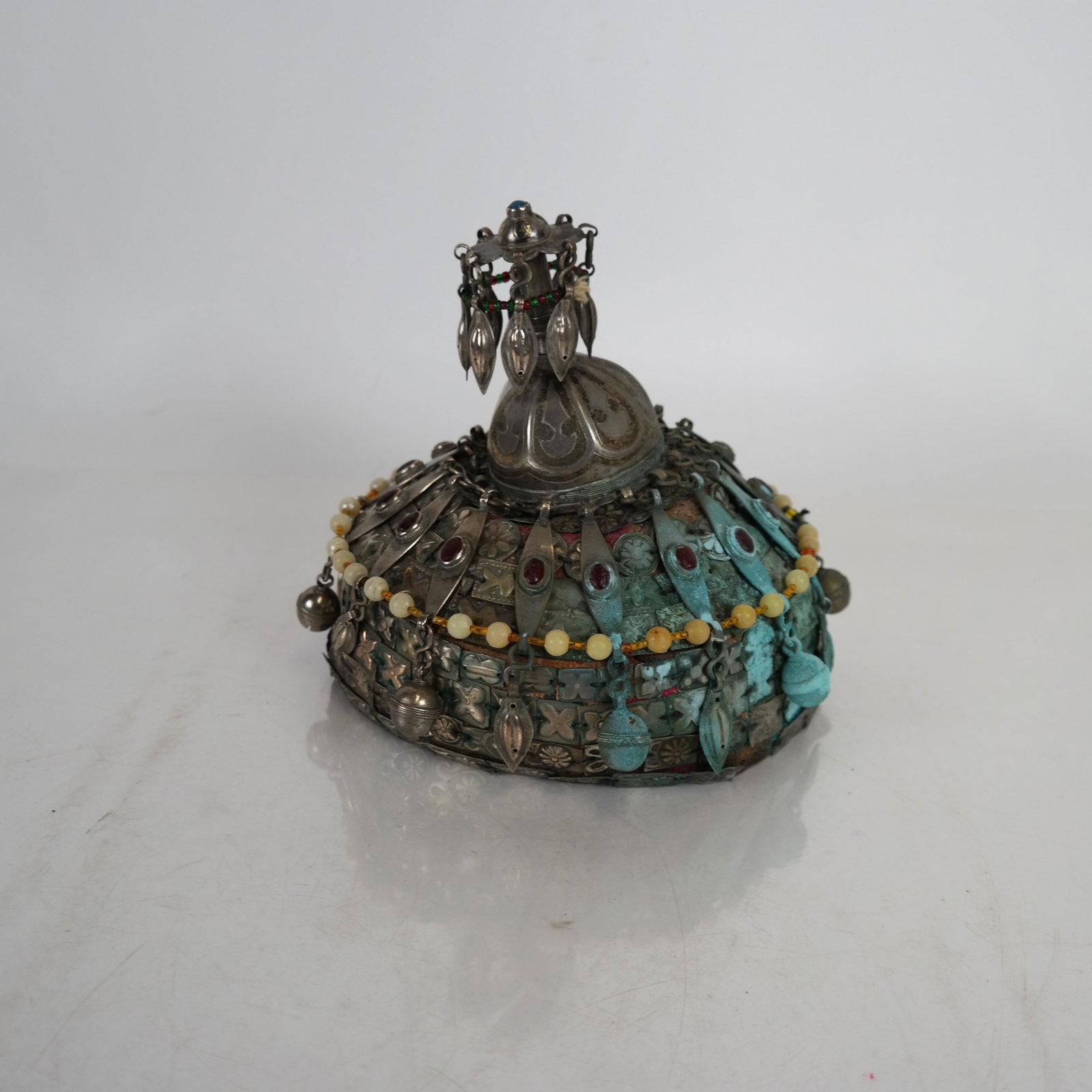 Antique Asian Silver Embellished Hat: Asian cloth hat covered with silver squares, surmounted by a decorated finial, embellished with carnelian and jade beads. [7 x 7 (dia) inches]. Verdigris; wear as with age.