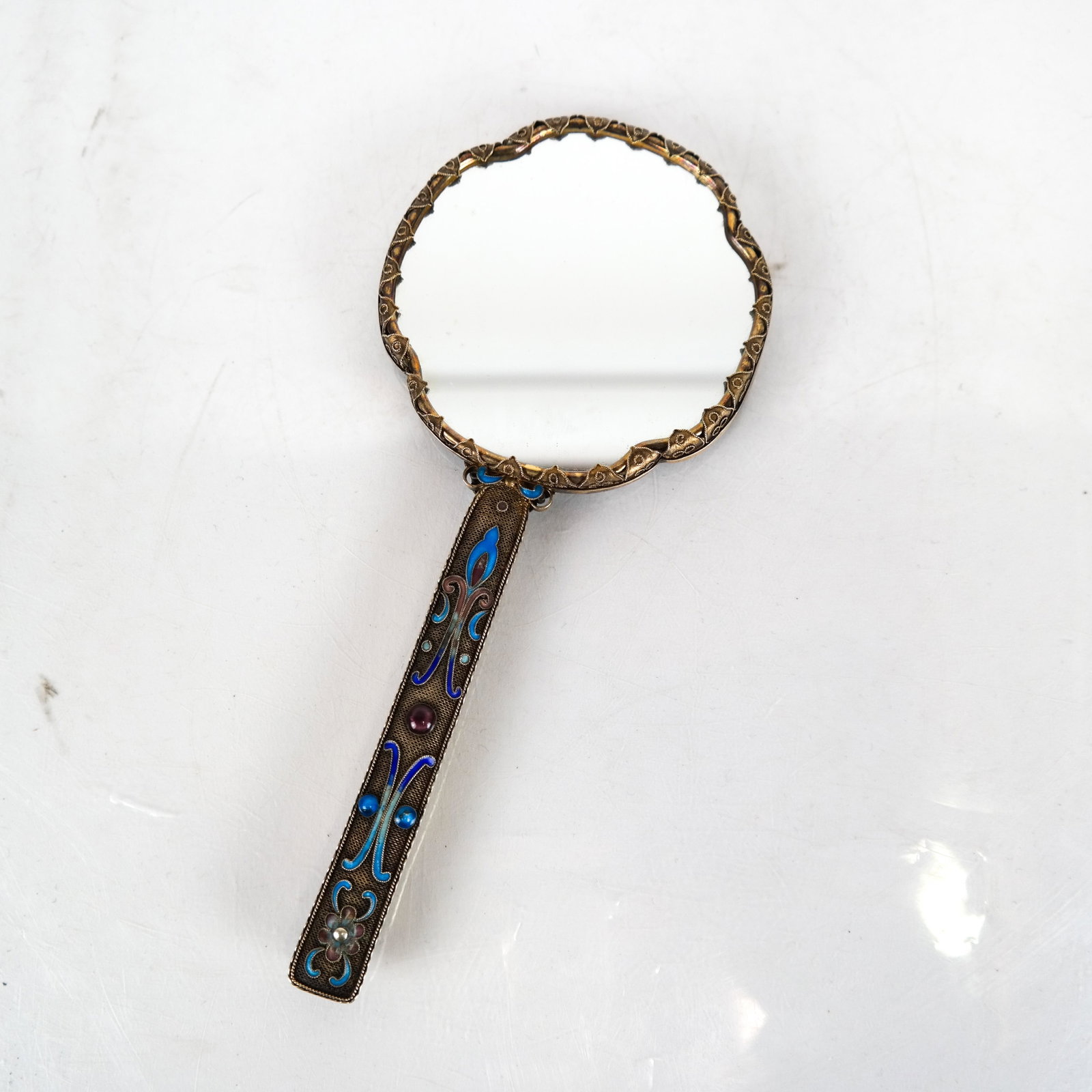 Chinese Jade and Enamel Hand Mirror: Chinese jade, enamel handle and top, with inset reticulated figural scene. [7 x 3 (dia) inches]. In good condition.