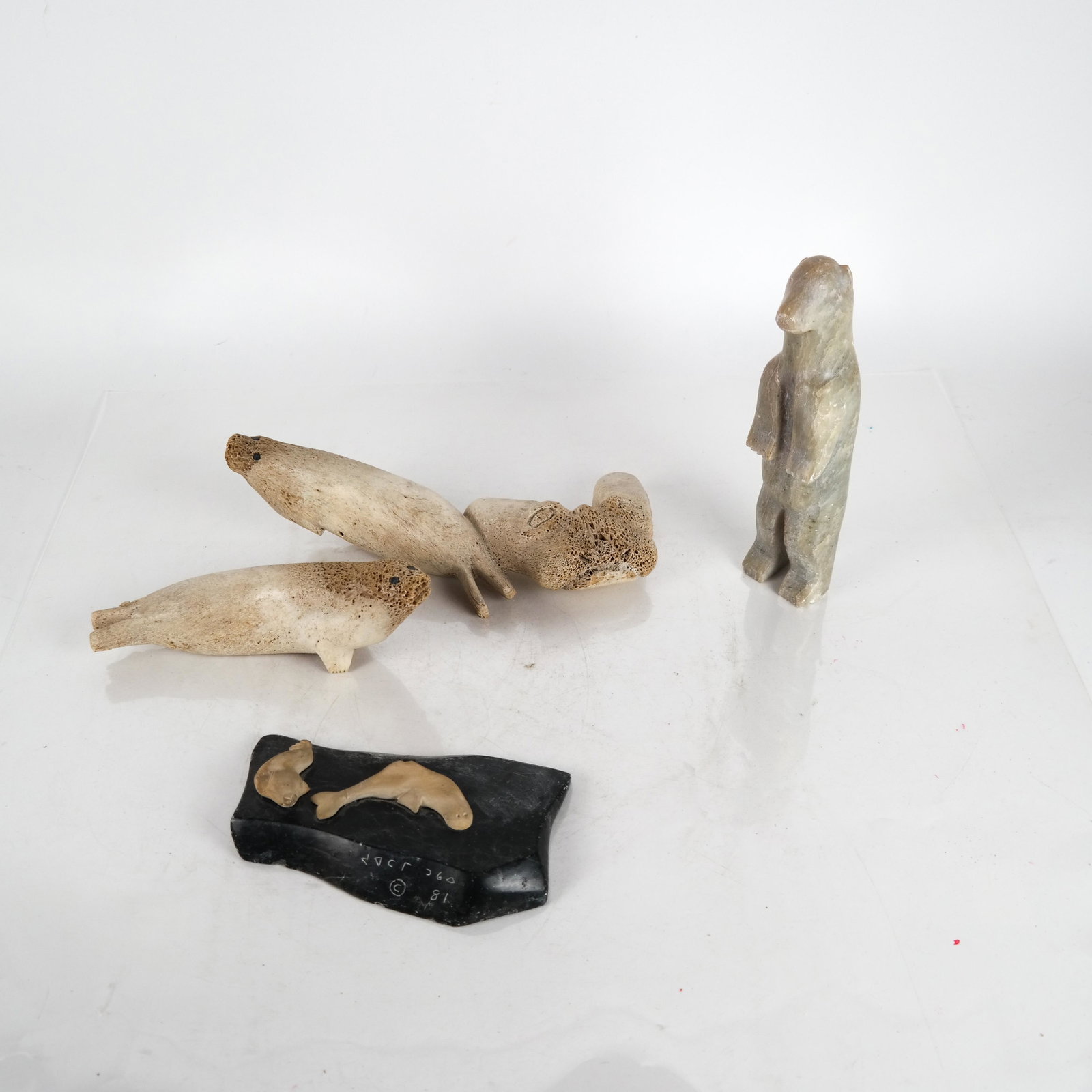 4 Inuit/Eskimo Sculptures: An Inuit sculpture of two walruses on a flat rock (small crack across one walrus's tail), two carved bone sculptures, and a polar bear. [Largest: 11 inches long].