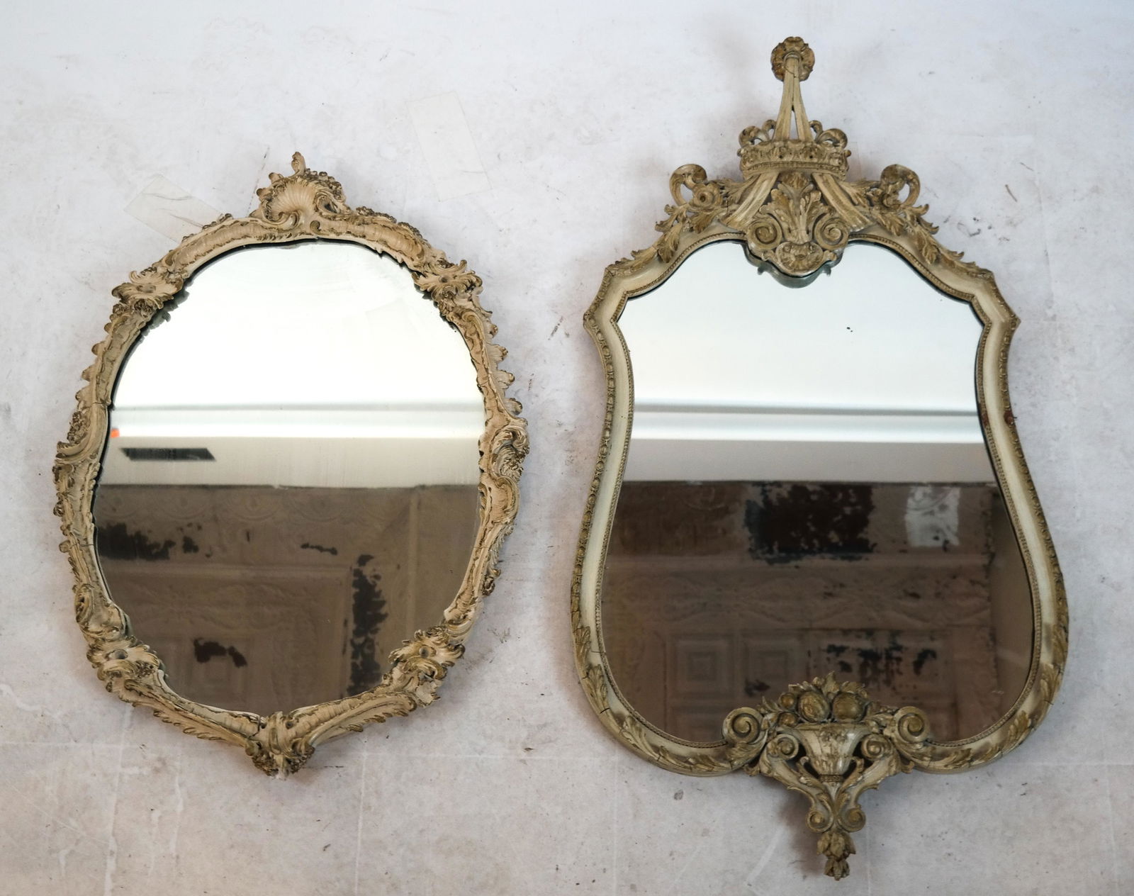 Two Antique Mirrors in Carved Wood Frames: Two mirrors in carved wood framed. [Shaped: 45 x 24 inches; Oval: 33 x 25 inches]. Missing and loose elements; wear; splits.