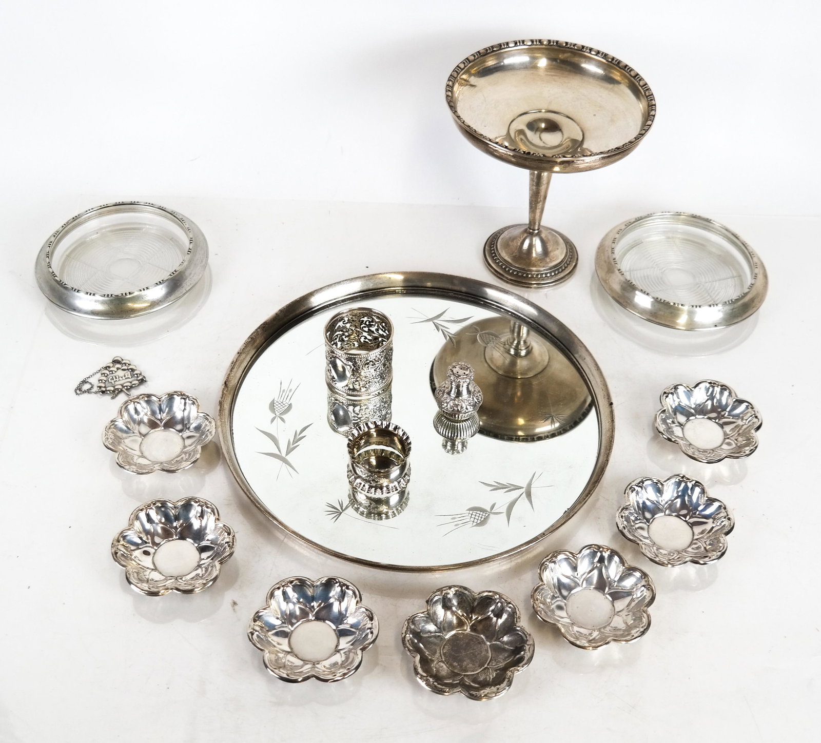 18 Sterling and Silver Plate Items: Lot includes a mirrored tray [11 (dia) inches]; 10 sterling silver nut dishes, by Rogers [3 (dia) inches]; 2 silver plate napkin rings and a salt shaker; a weighted sterling silver tazza [6 1/4 x 6 1/