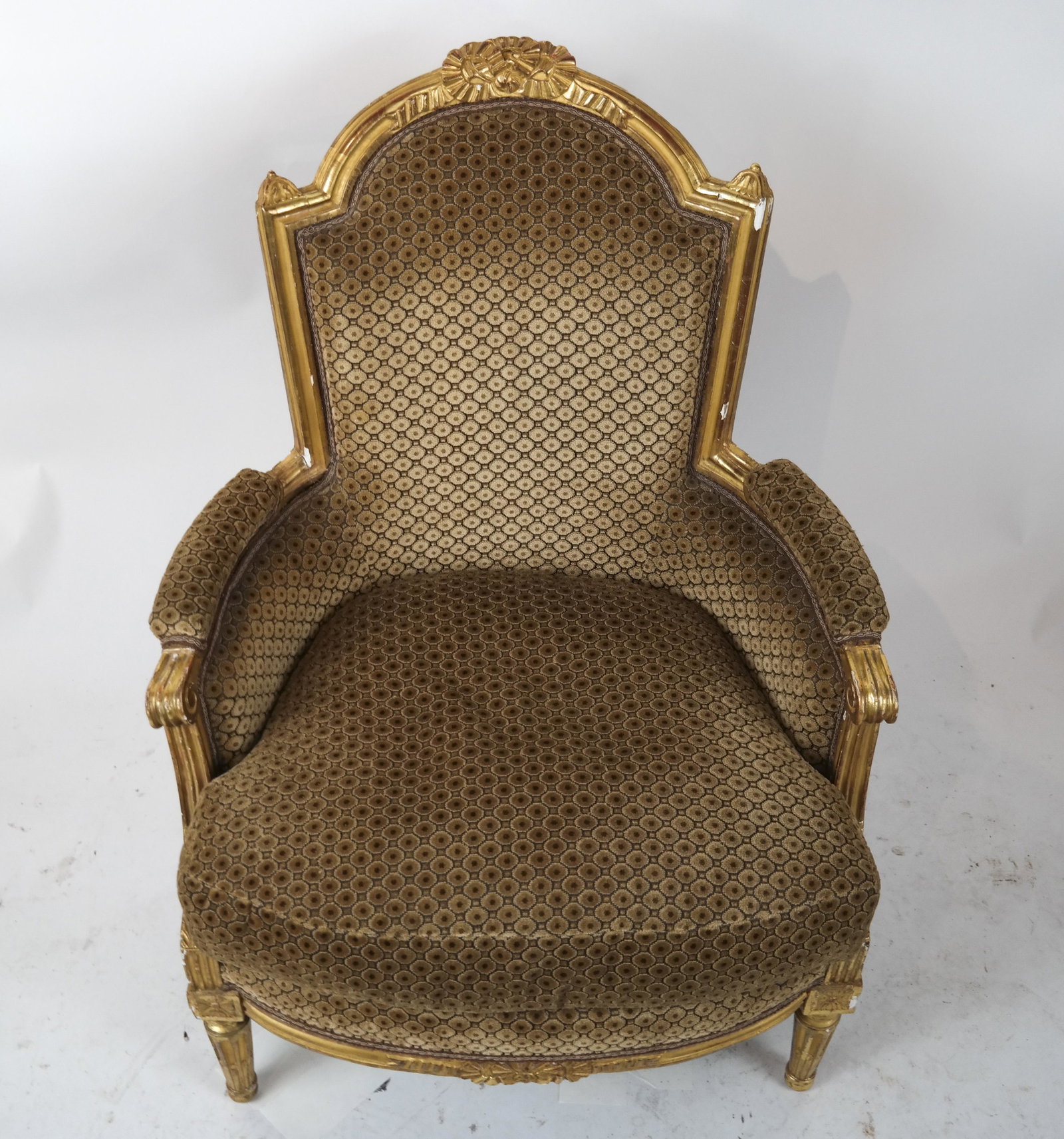 Louis XVI Gilt Wood Bergere: Louis XVI gilt wood bergere with arched padded back centered by a bow, seat rail with conforming decor, tapered fluted legs. Circa 1770. Cut brown velvet upholstery.