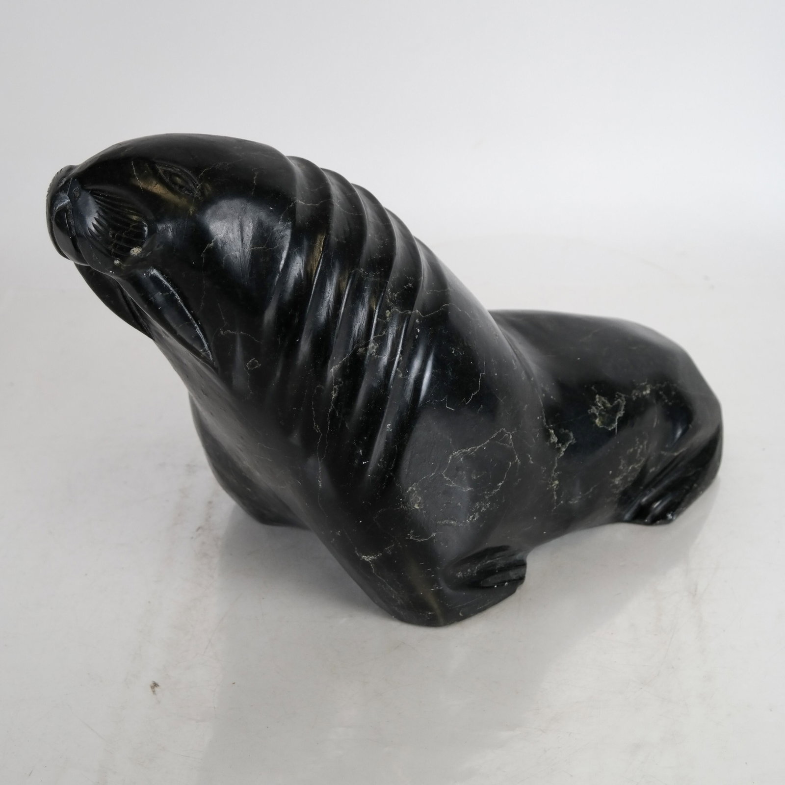 Inuit Stone Seal: Inuit carved stone seal, with label on base. [10 x 15 x 7 inches]. Abrasions.