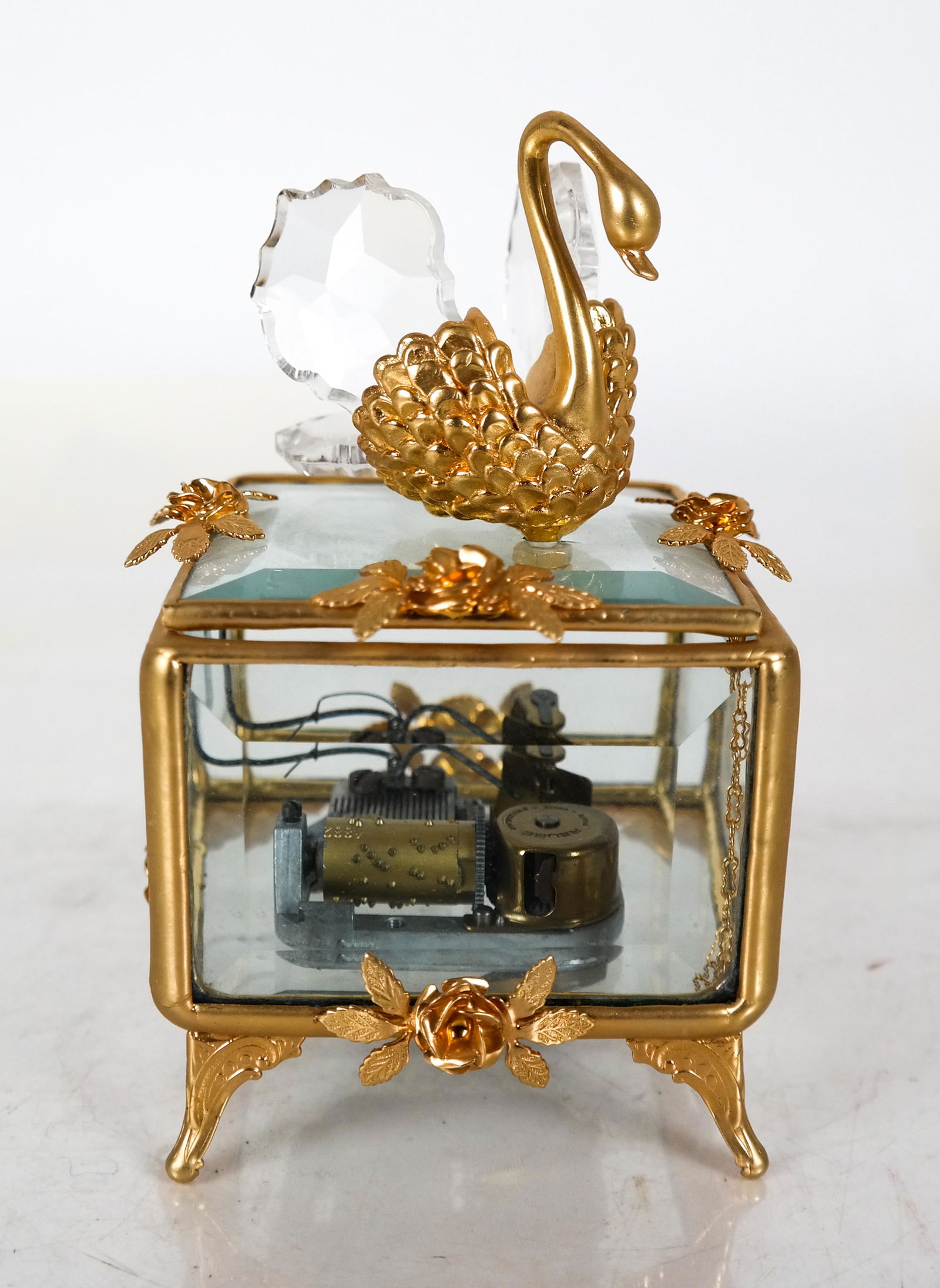 Reuge Crystal Swan Music Box: Crystal Swan beveled glass music box, by Reuge. The swan, having a gold body and large crystal wings, is made by La Melodie Crystal Sculptures; the box has beveled glass panels, gold trim, gold roses