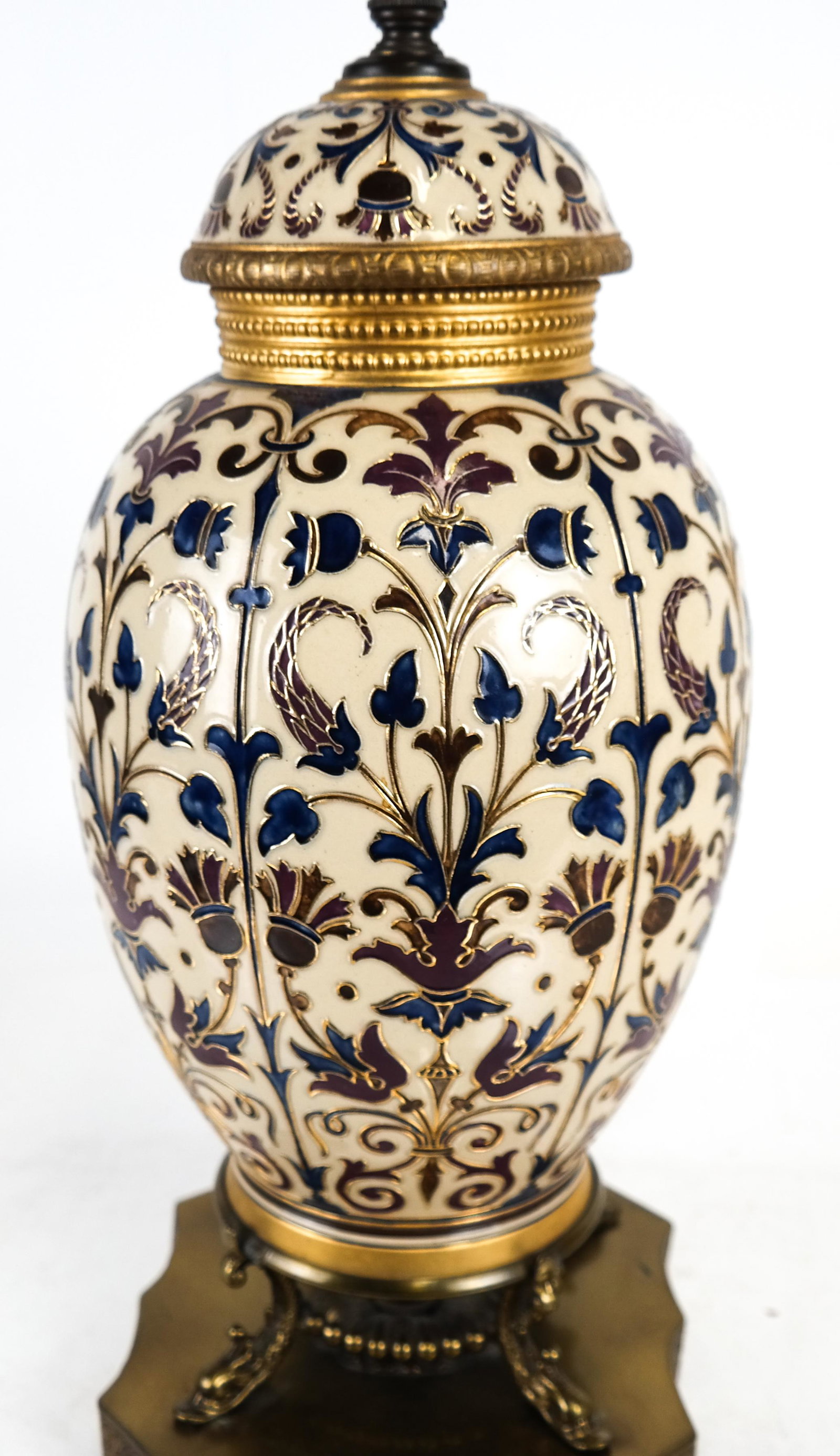 French Relief Decorated Porcelain Lamp: French relief decorated porcelain lamp on a brass dolphin footed base. [22 x 7 x 7 (base) inches]. In good condition.
