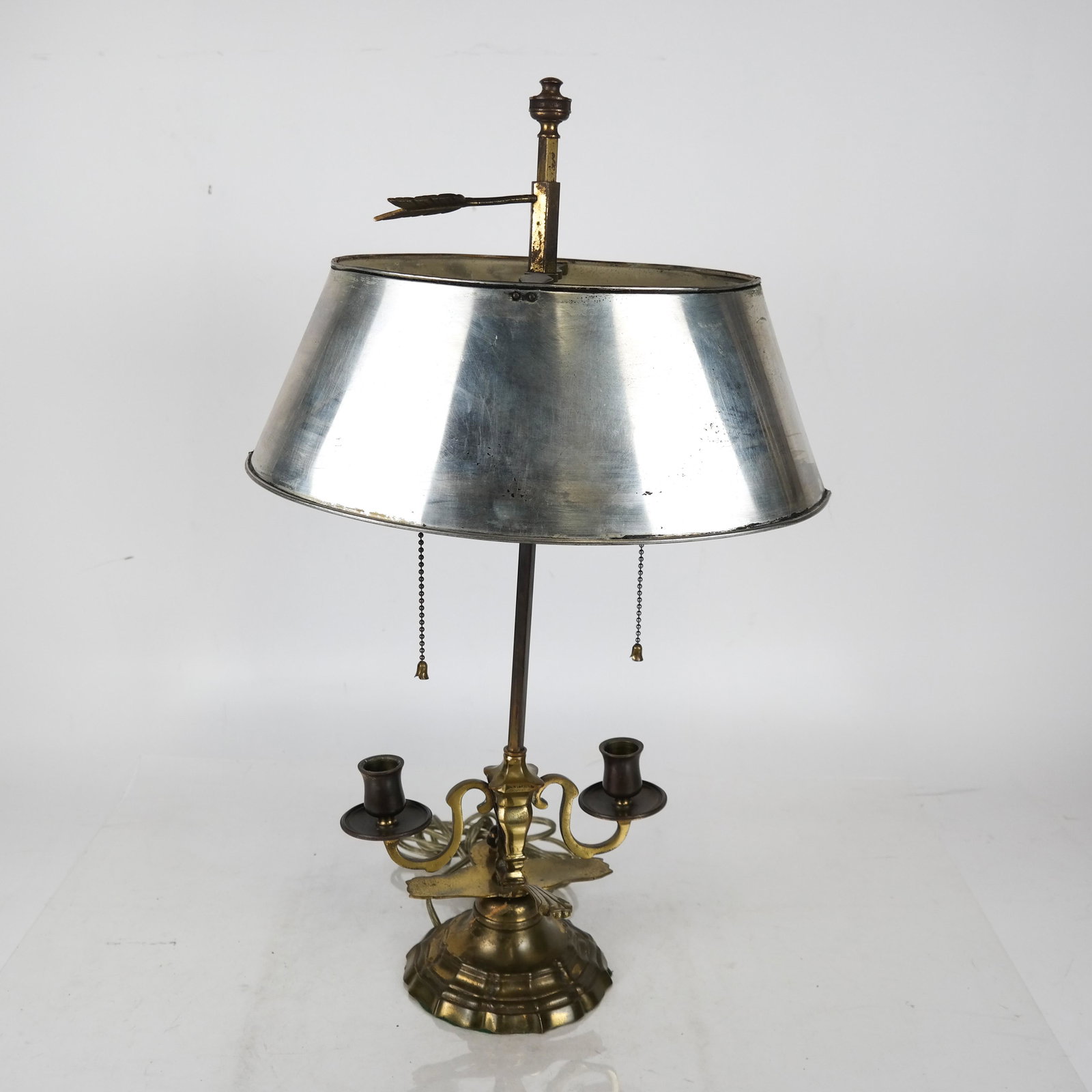 French Bronze Bouillotte Lamp: French bronze bouillotte lamp, with silver tole shade, in spoon design. [Lamp: 21 1/4 x 8 x 6 inches; Shade: 5 x 13 1/4 x 9 inches; Base: 5 (dia) inches]. Patina worn.