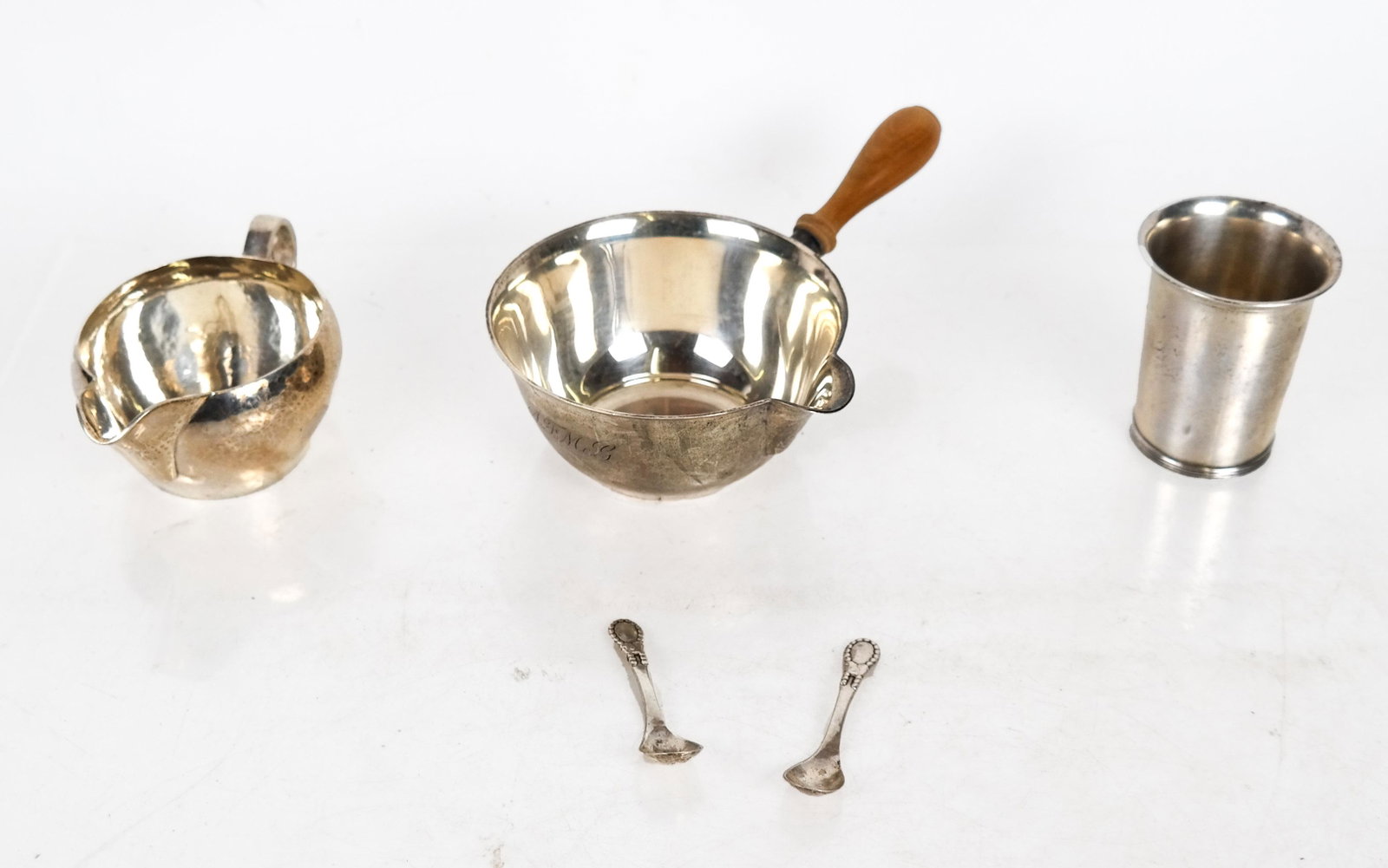 Sterling Silver and 830 Silver Group: Sterling silver items include a Tiffany melting pot, a creamer, a beaker, and two 830 silver salt spoons. 13.90 ozt., inclusive. In good condition.