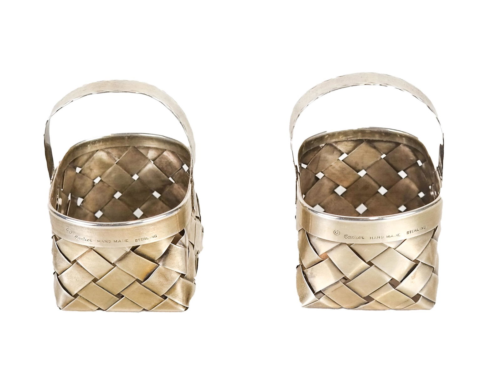 Pair of Sterling Silver Cartier Baskets: Vintage handmade sterling silver woven Cartier trinket boxes, in the form of handled baskets, stamped "Cartier Handmade Sterling". [Approx. 3 x 2 1/2 x 2 1/2 inches]. Damage to one band.
