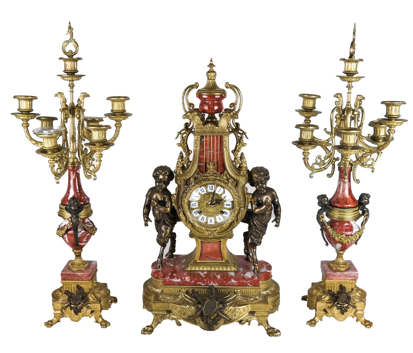 French-Style 3-Piece Clock Garniture: Three-piece rouge marble and gilt bronze clock set, including cherubs on a mantel clock. [27 x 10 (dia) inches (x2); 24 x 13 x 8 inches]. Loose construction.