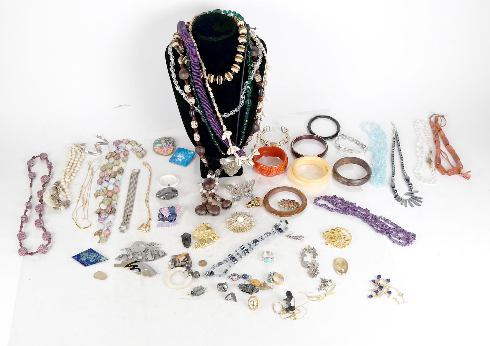 Bag of Costume Jewelry: Costume jewelry lot inludes semi-precious stones, wood, malachite and shell pieces, as well as a sterling silver pin.
