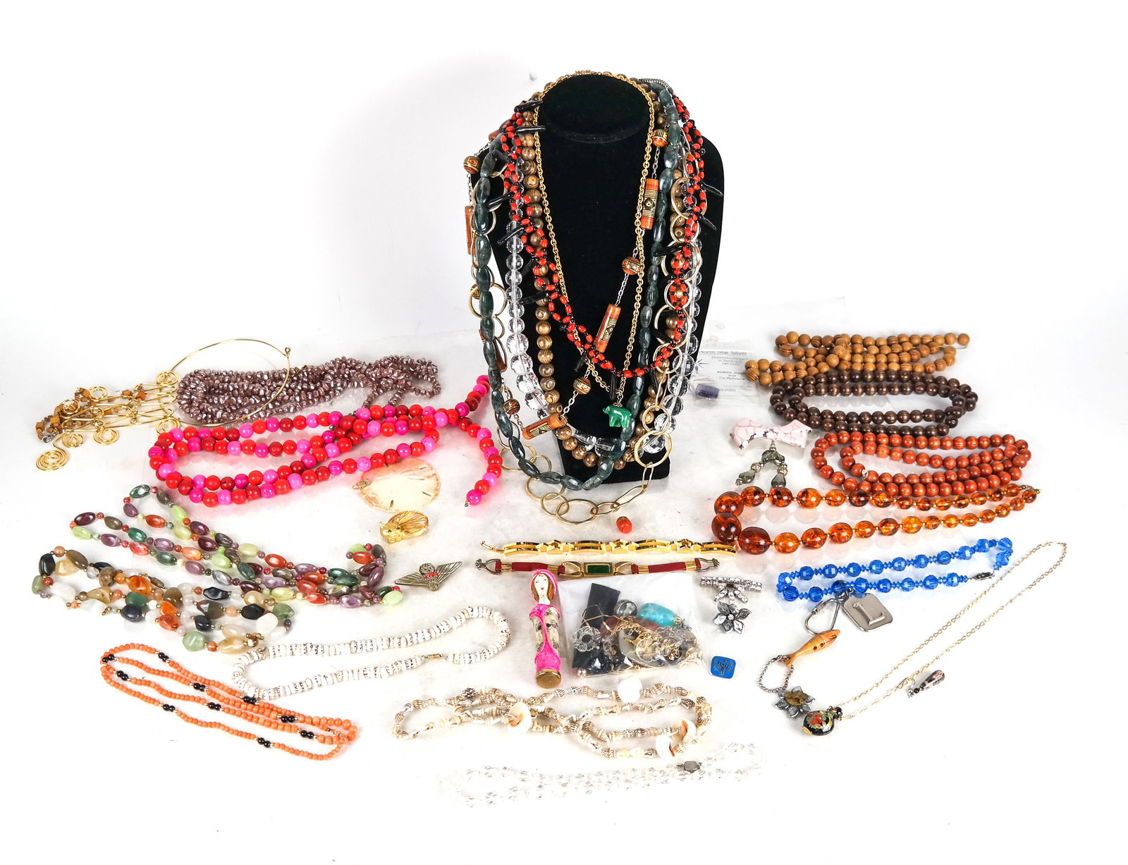 Bag of Costume Jewelry: Costume jewelry lot inludes semi-precious stones, wood, malachite and shell pieces, as well as a sterling silver pin.