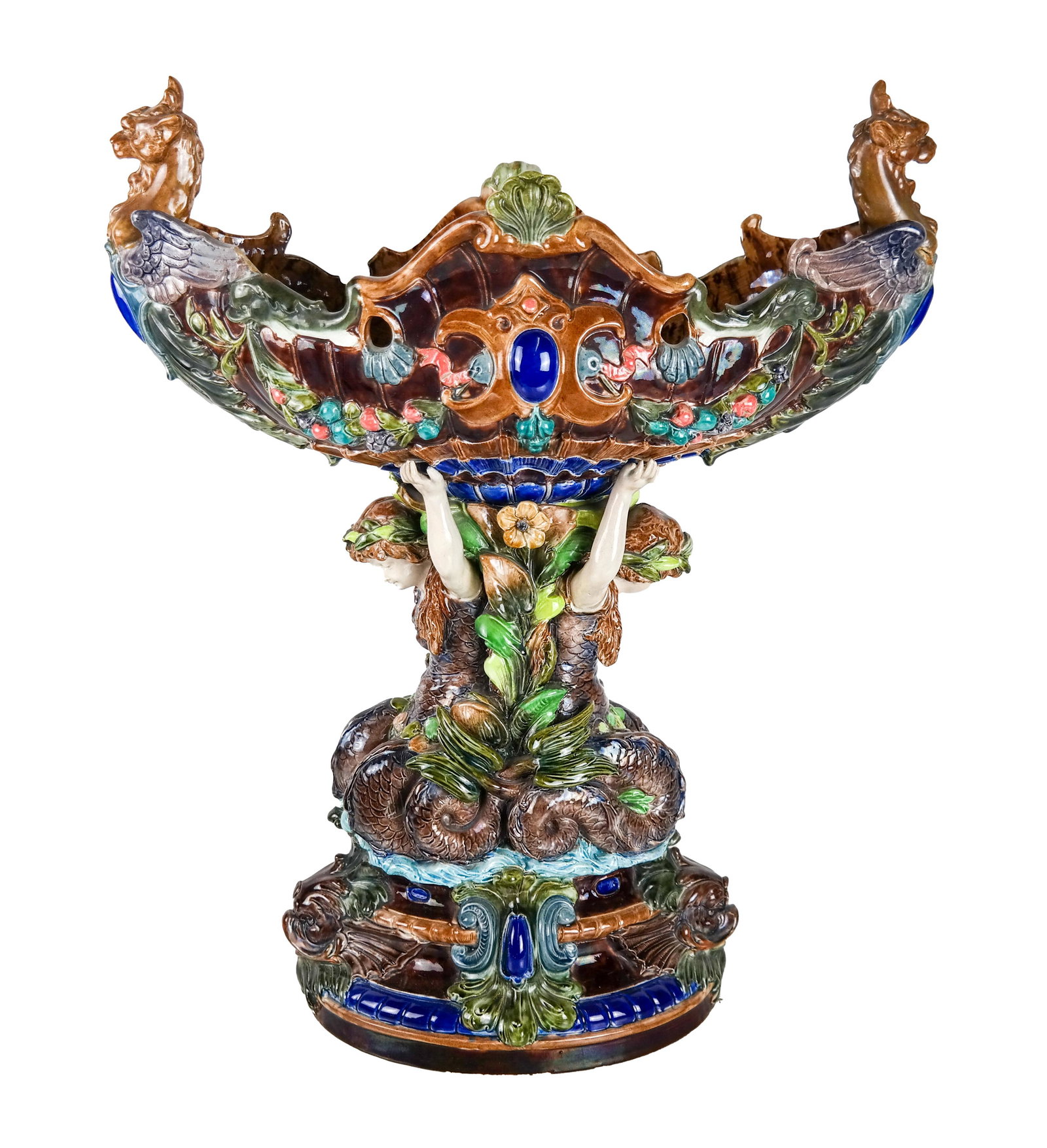 Majolica Centerpiece Bowl: Majolica centerpiece bowl with caryatids and lion's head motifs. Provenance: From the Estate of Bernard Castro, of the iconic Castro Convertible Company. [20 1/2 x 17 x 8 inches]. One loss to rim.