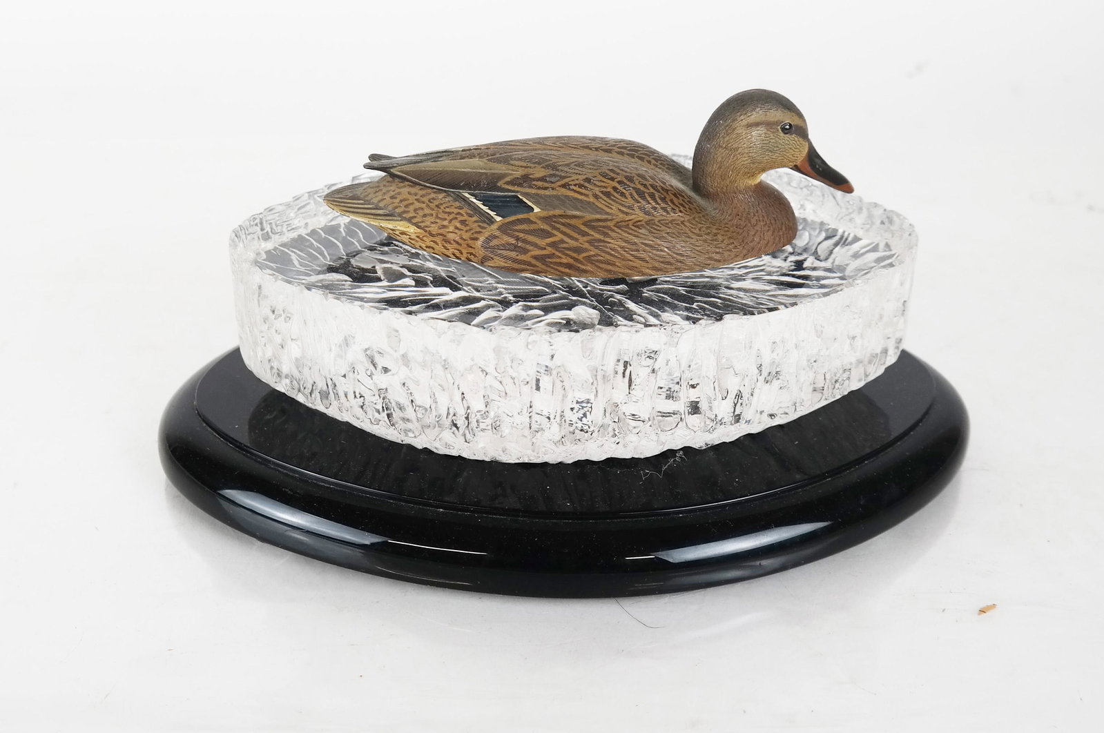 Bronze Mallard by Val Bennet for CARTIER: Cartier colorless glass and patinated bronze Mallard, designed by Val Bennett, ca. 1976, realistically modeled and enameled, appearing to float on water. Marked on the bottom, on a glass base. Duck no