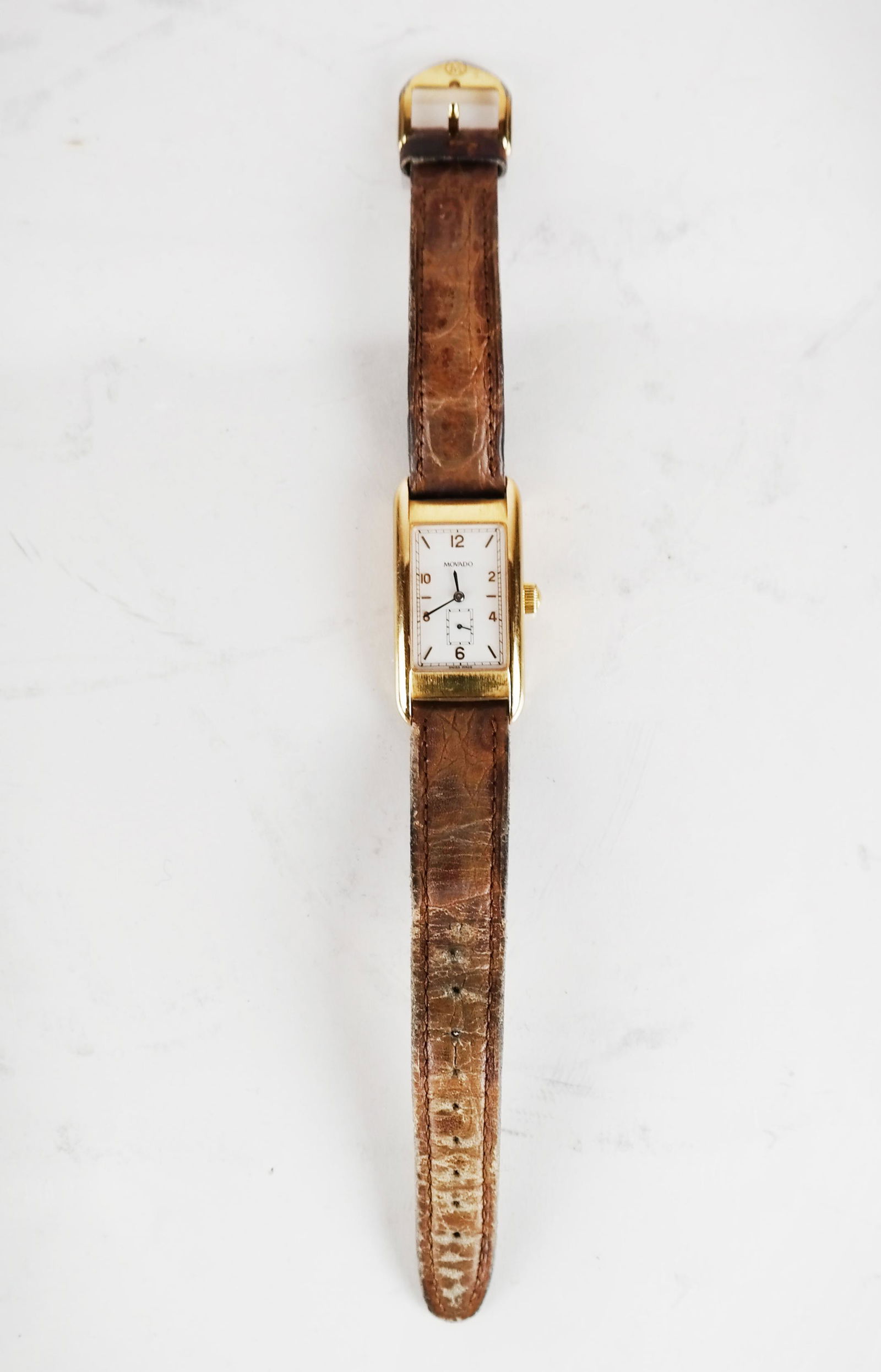 Movado 18K Gold Manual Wind Wristwatch: Movado 18K yellow gold rectangular watch, "No. 135" inscribed on reverse, water resistant. [Case: 1 1/8" L x 15/16" W]. Case in good condition; strap worn. Not tested.