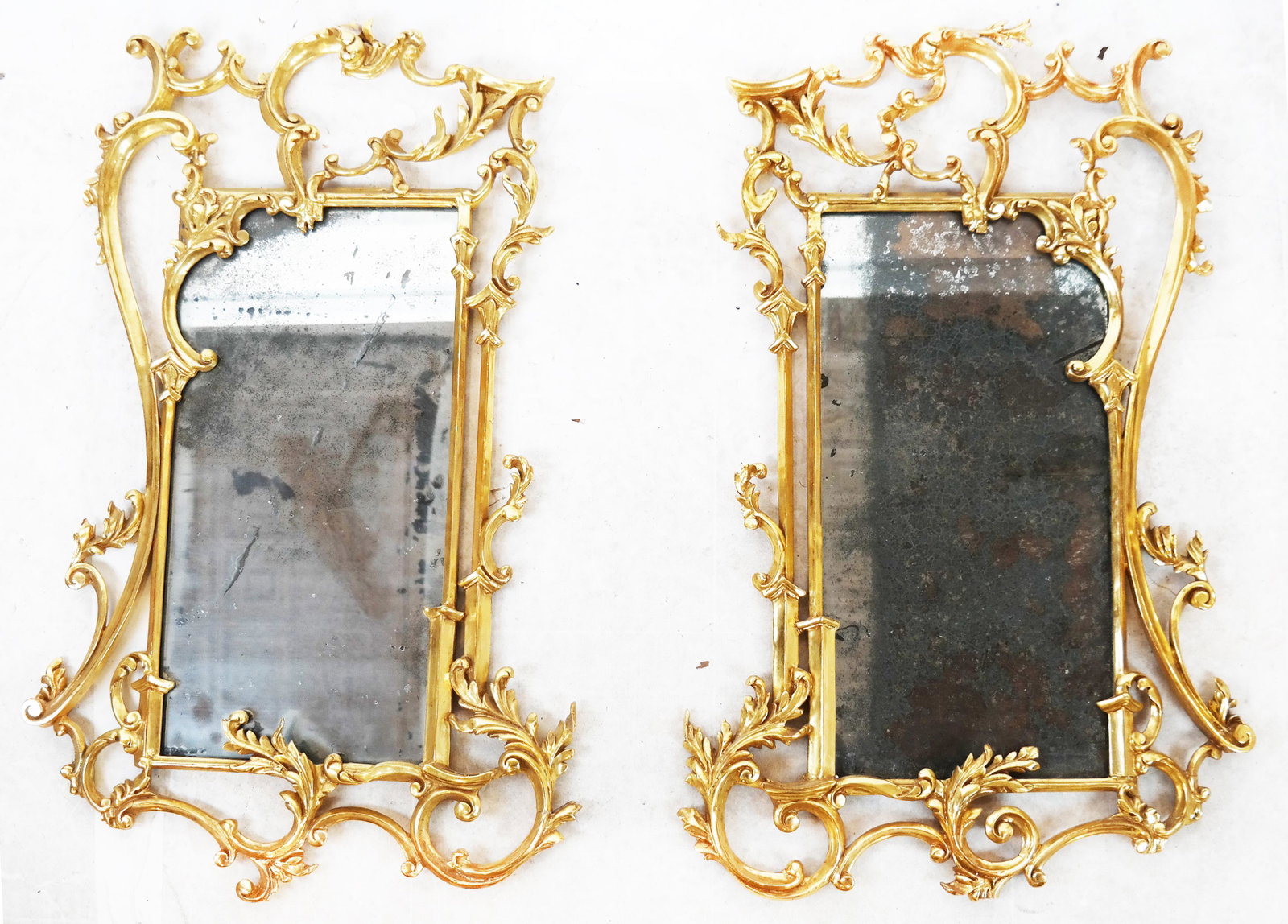 Matched Pair of Rococo Gilt Wood Mirrors: Matched pair of asymmetrical rococo-style gilt wood mirrors. [37 1/2"H x 23" W]. Silvering; frame losses.
